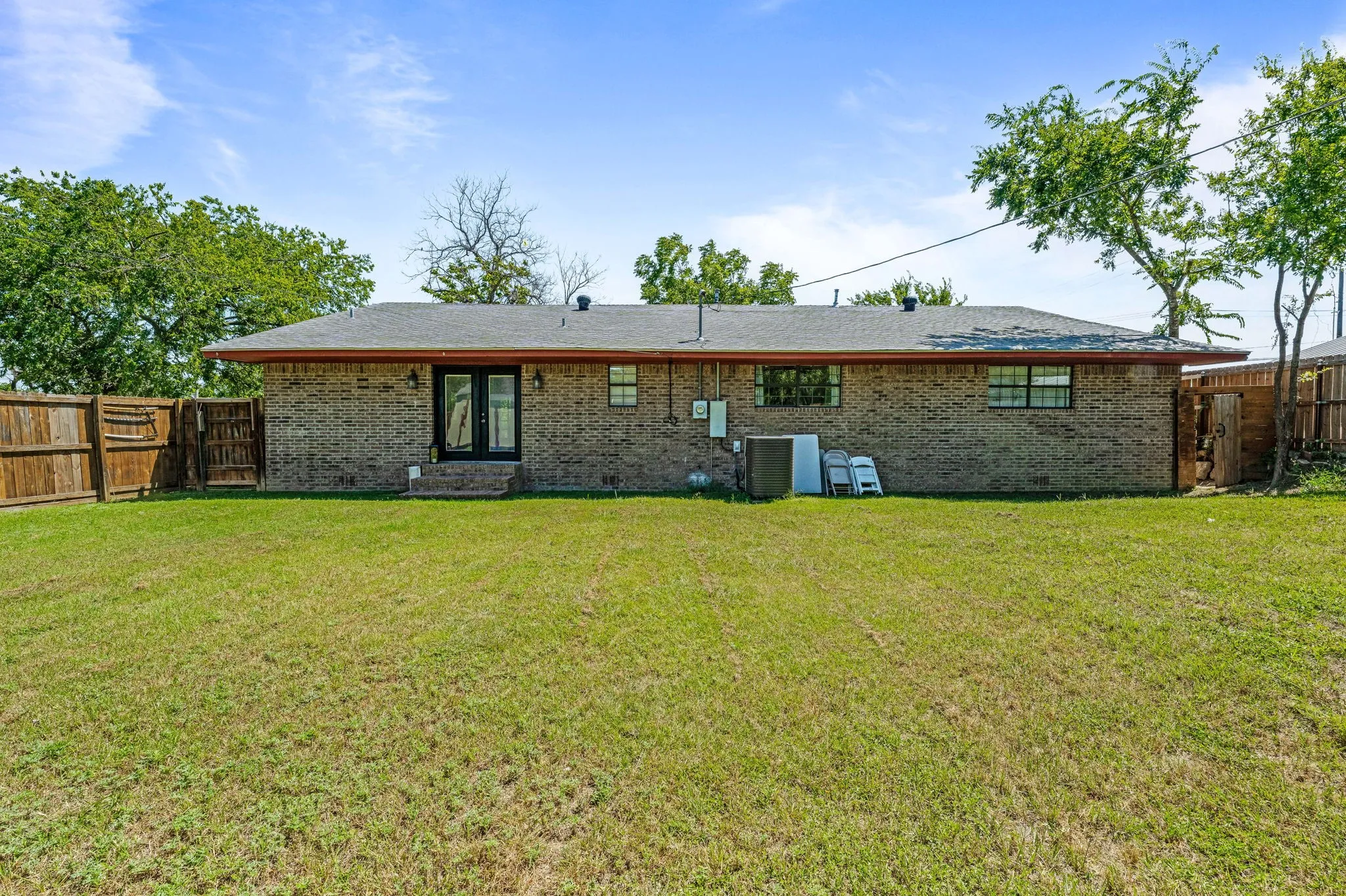 Back of house with brick siding and a fenced backyard