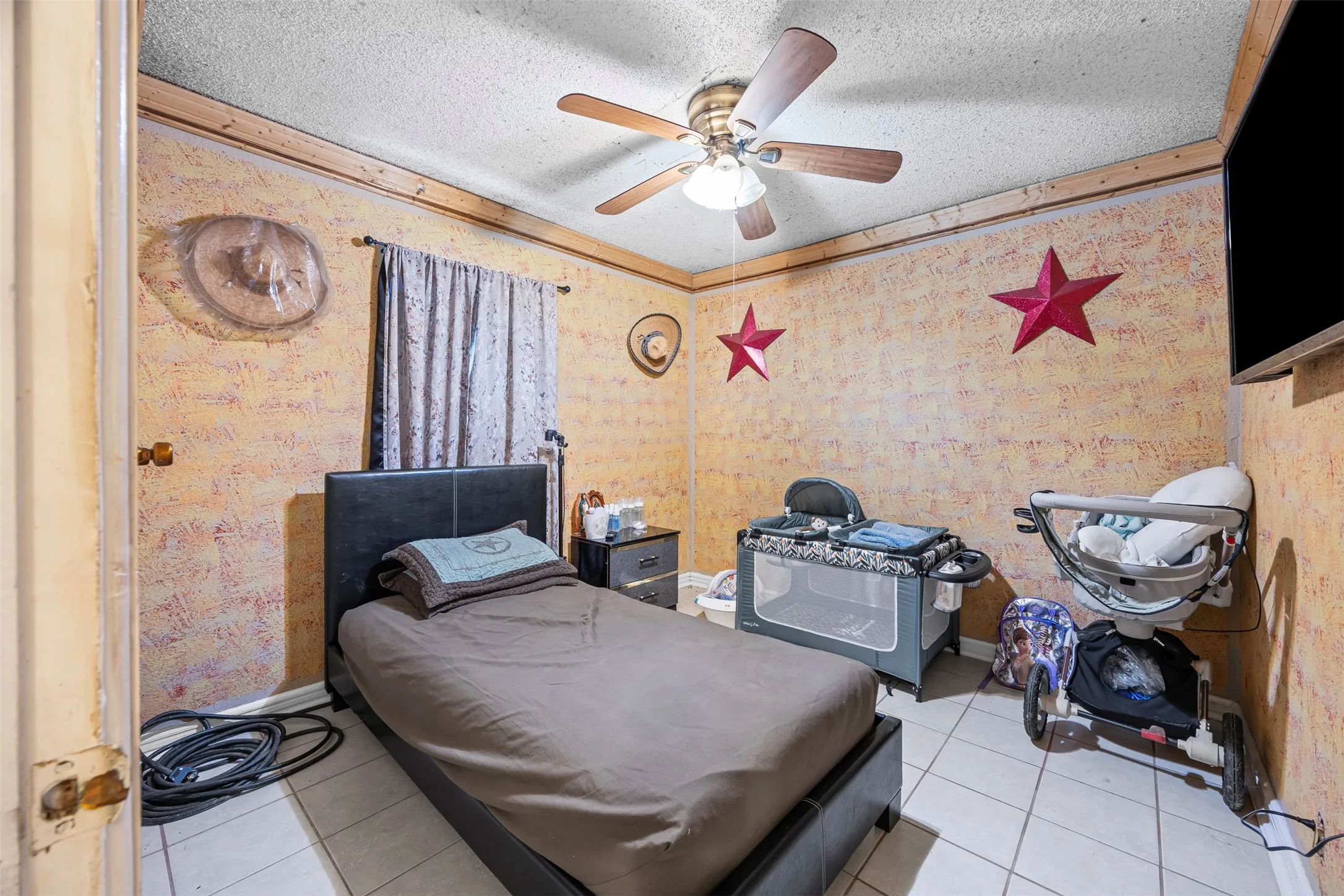 Bedroom featuring a textured ceiling, tile patterned flooring, wallpapered walls, and a ceiling fan