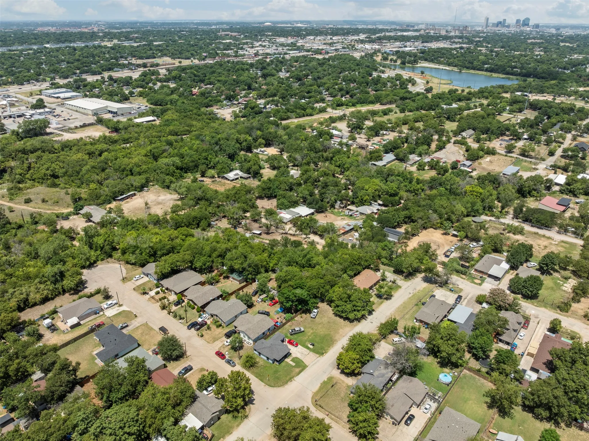 Aerial view of residential area with a large body of water and a tree filled landscape