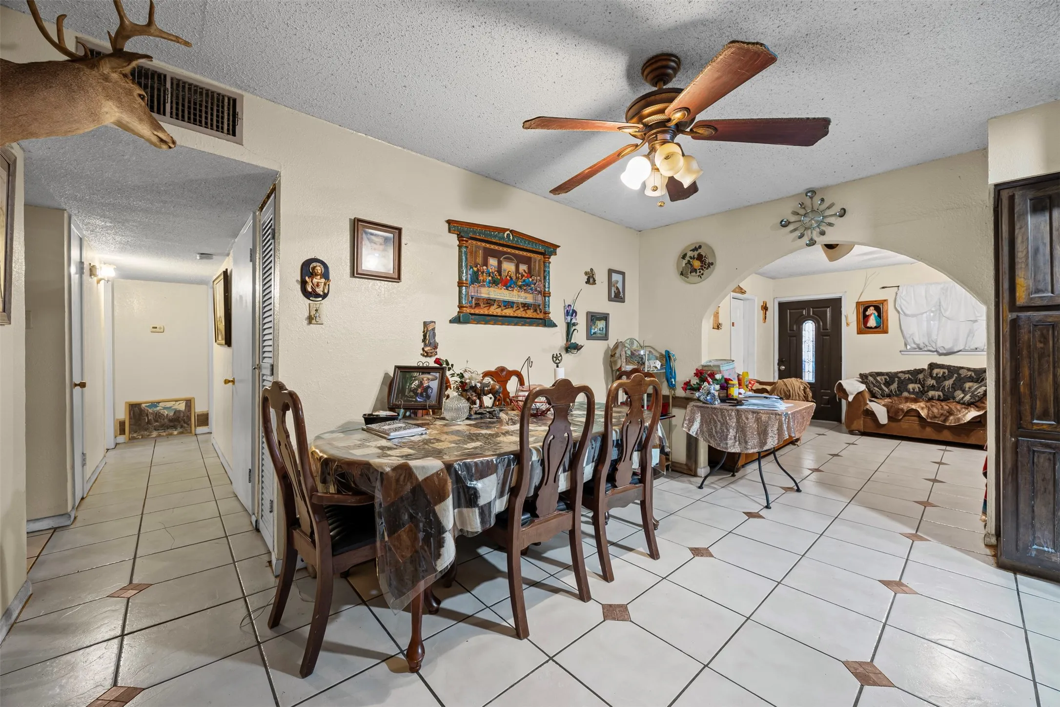 Dining space with a textured ceiling, arched walkways, ceiling fan, and light tile patterned floors
