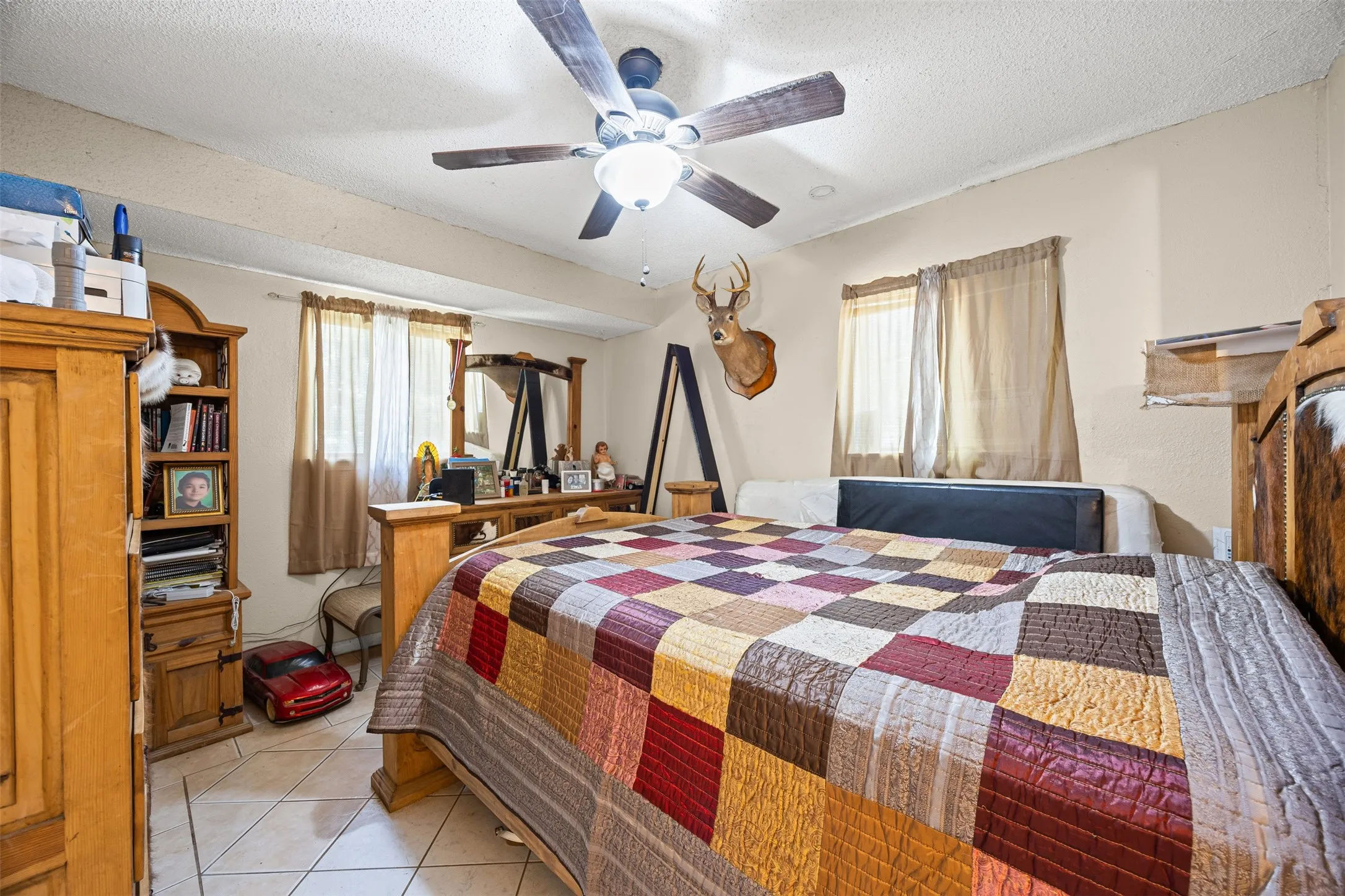 Bedroom featuring a textured ceiling, light tile patterned flooring, and ceiling fan