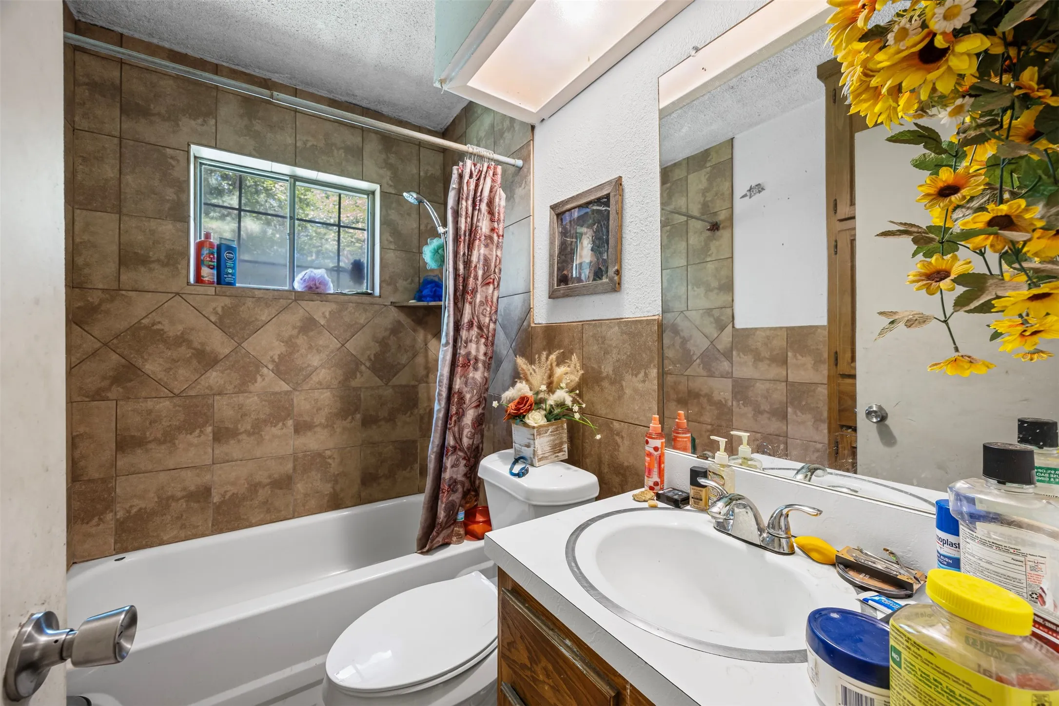 Full bathroom with vanity, shower / tub combo, a textured ceiling, and tile walls