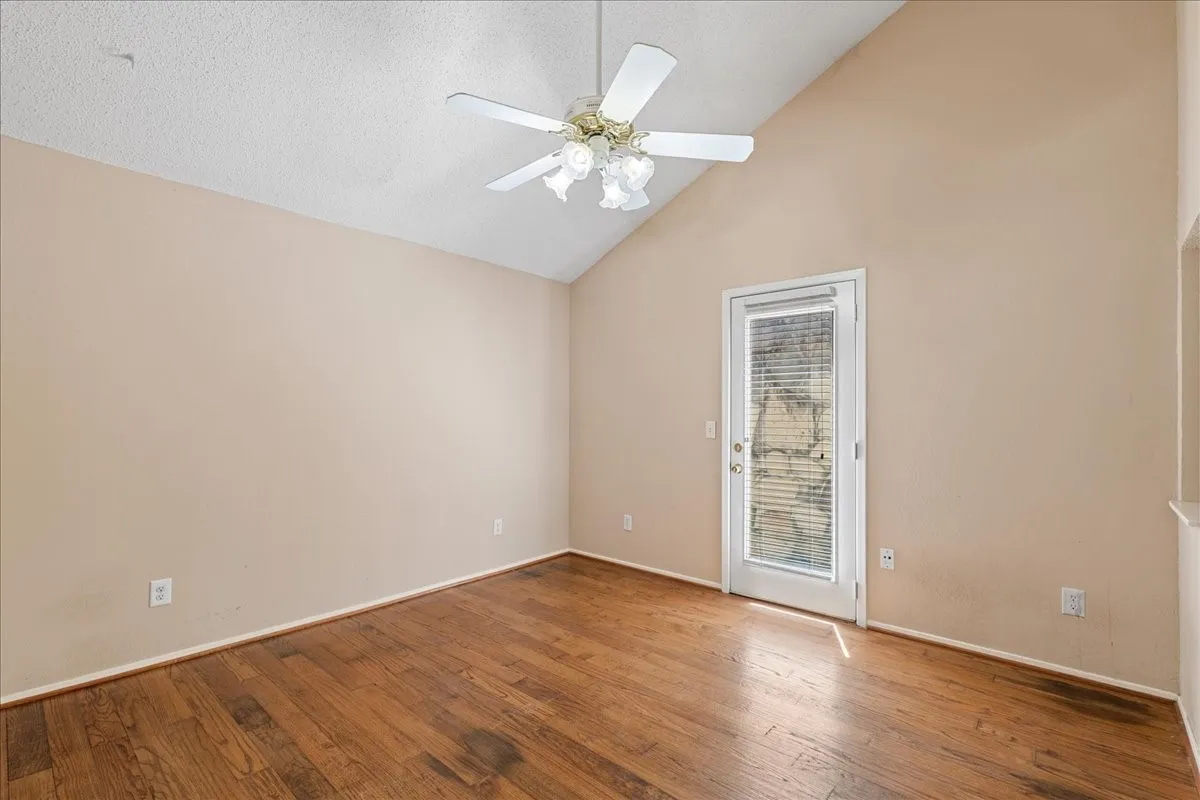 Unfurnished room with vaulted ceiling, wood-type flooring, ceiling fan, and a textured ceiling