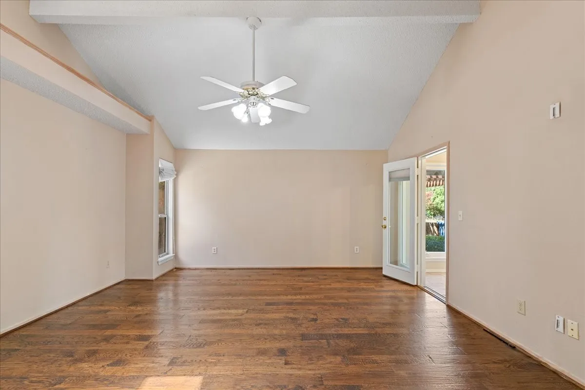 Empty room featuring wood finished floors, ceiling fan, and high vaulted ceiling