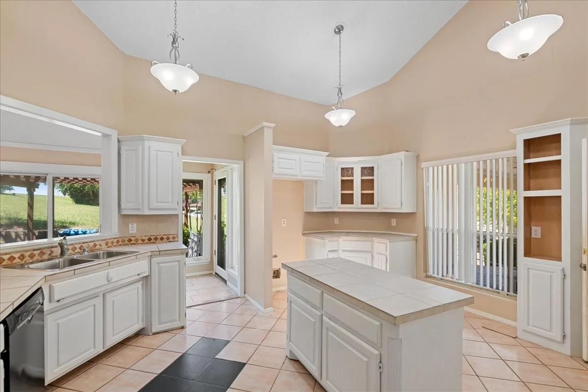 Kitchen featuring tile counters, healthy amount of natural light, light tile patterned floors, and high vaulted ceiling
