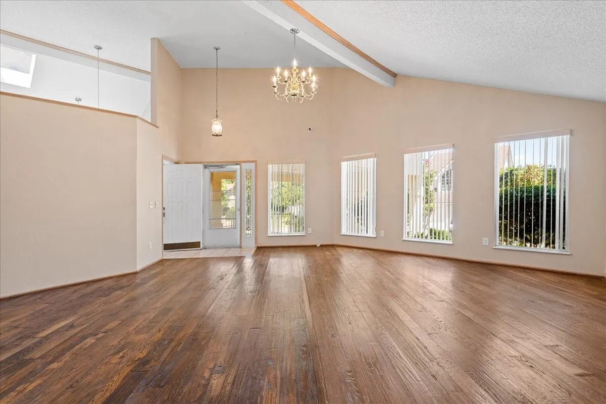 Unfurnished living room featuring wood-type flooring, a chandelier, and a textured ceiling