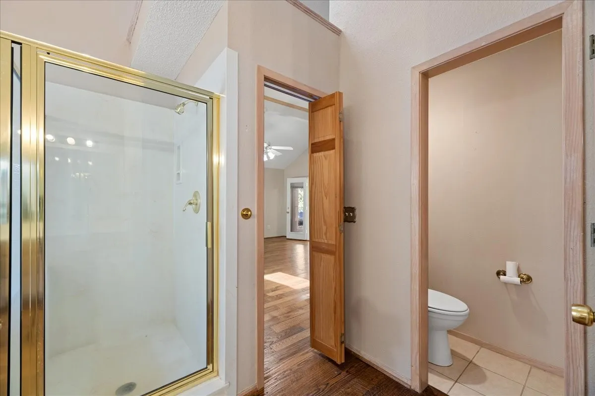 Full bath with a stall shower, wood finished floors, and a ceiling fan