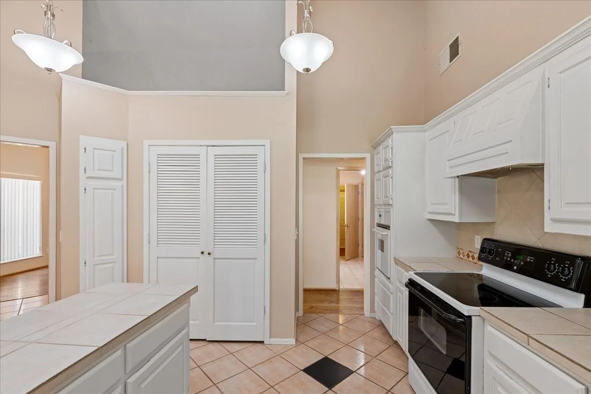 Kitchen featuring tile countertops, white appliances, a high ceiling, and light tile patterned floors
