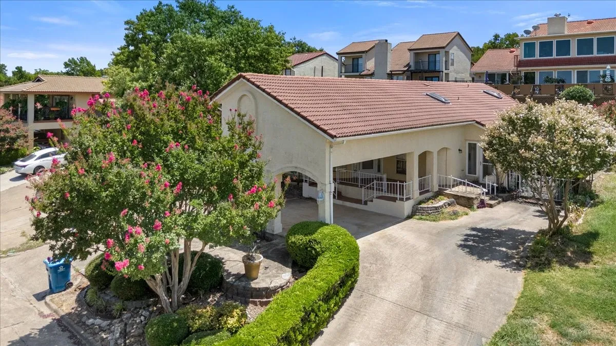 View of front of property with stucco siding, a tile roof, a porch, driveway, and a residential view