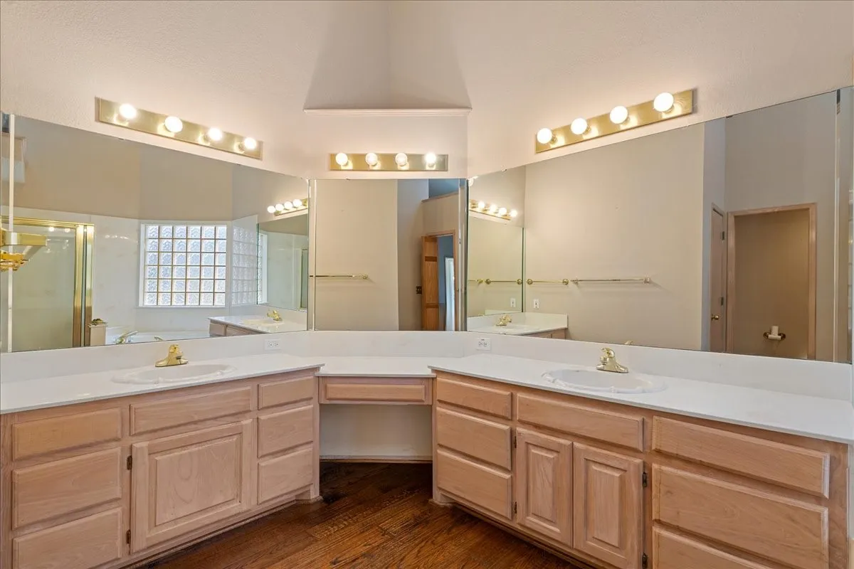 Bathroom with double vanity, a stall shower, wood finished floors, and a towering ceiling
