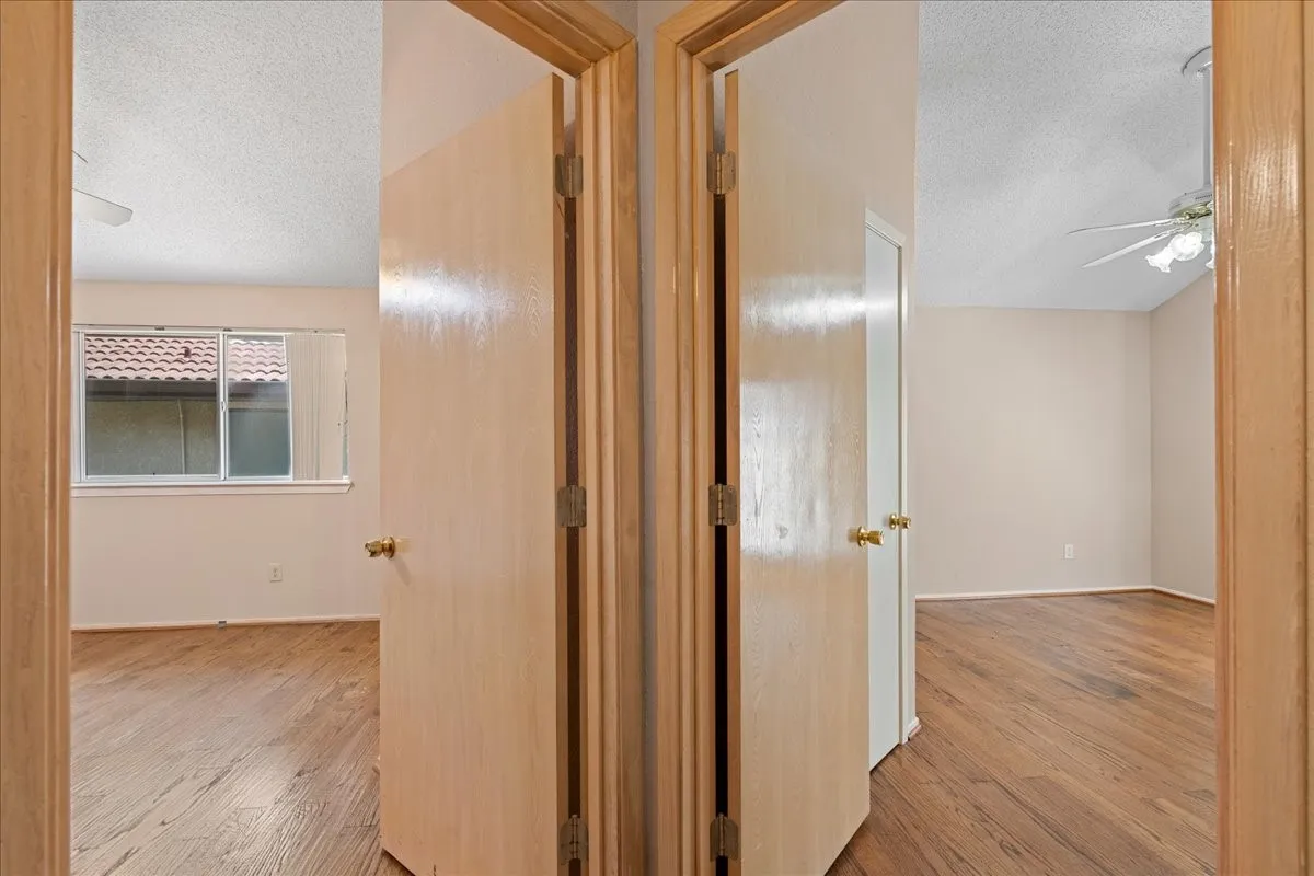 Hallway with a textured ceiling and wood finished floors
