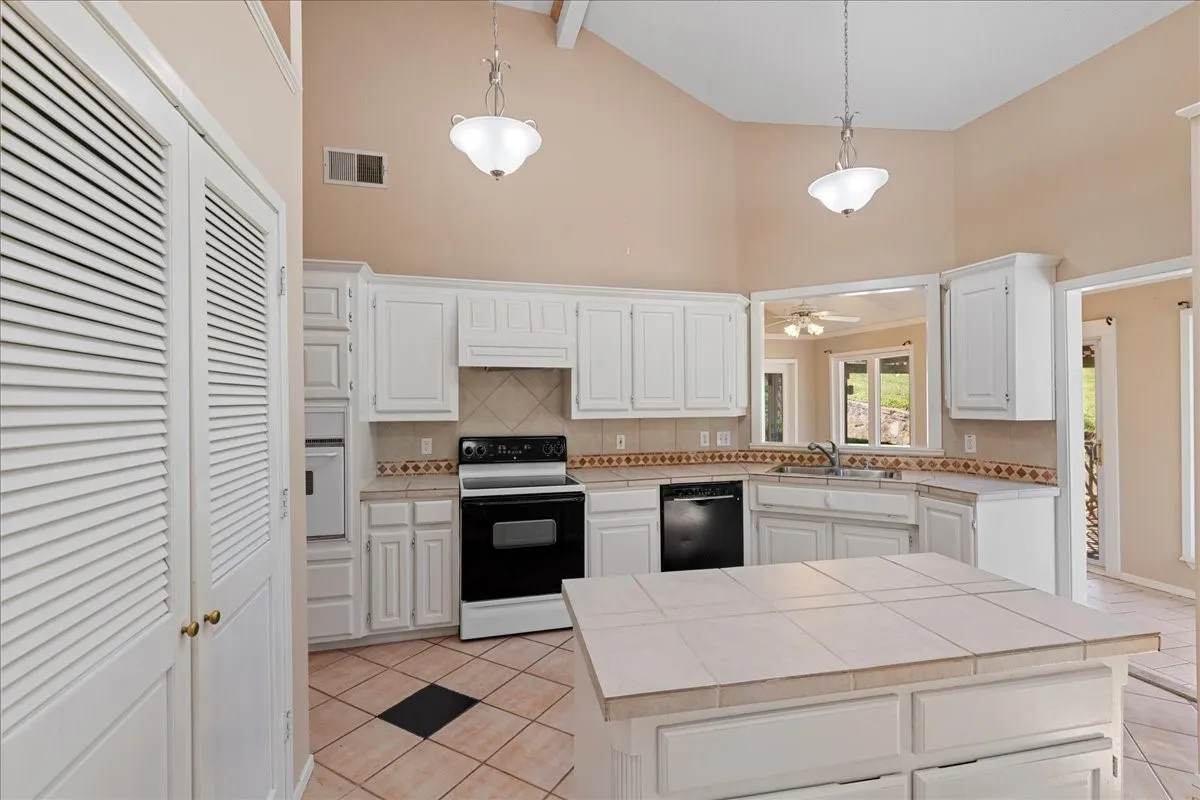 Kitchen with white appliances, light tile patterned flooring, high vaulted ceiling, tile countertops, and beam ceiling