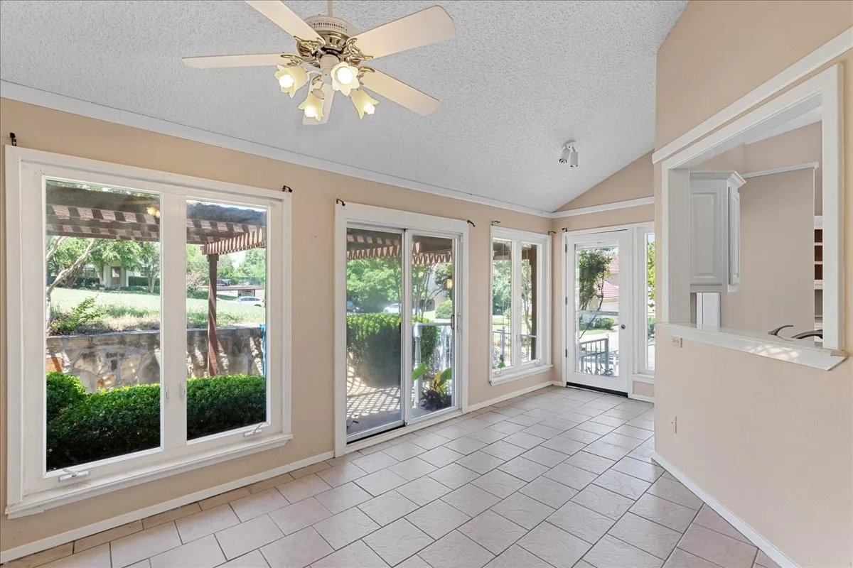 Unfurnished sunroom with a textured ceiling, tile patterned flooring, and lofted ceiling