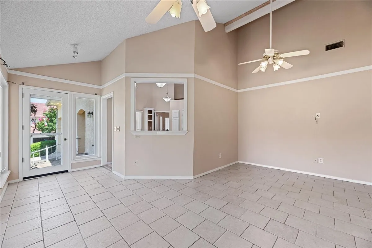 Empty room with ceiling fan, lofted ceiling, a textured ceiling, and tile patterned floors
