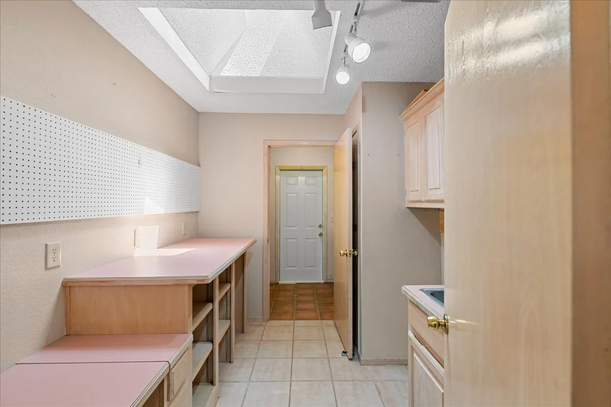 Laundry area featuring a textured ceiling, light tile patterned flooring, and track lighting