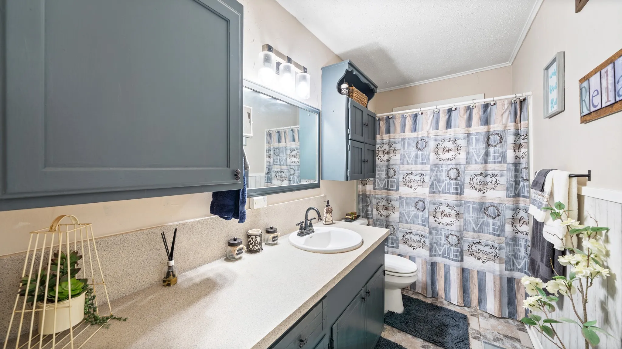 Bathroom vanity with integrated sink, wall-mounted mirror, overhead lighting, and built-in cabinetry