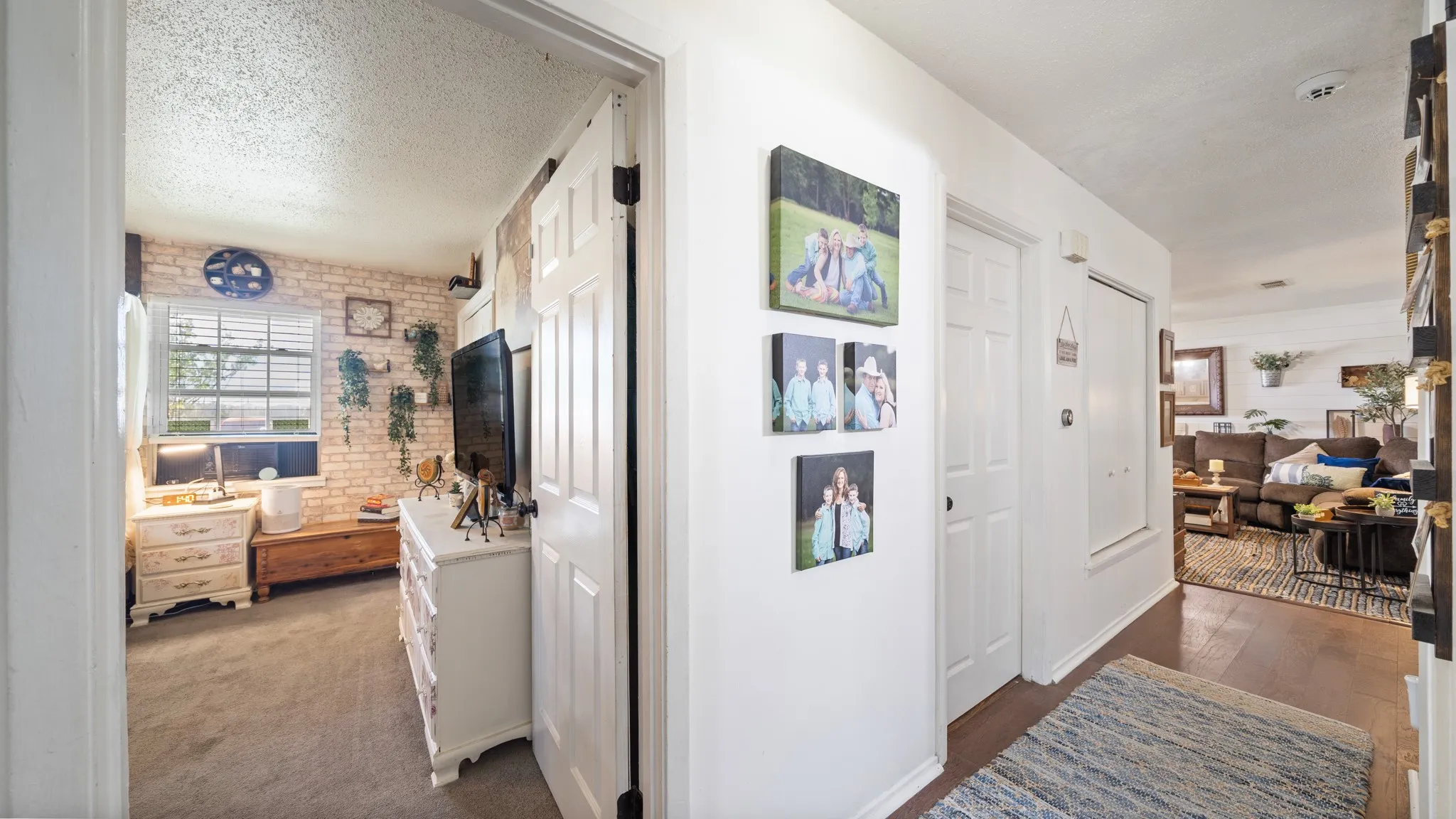 White paneled interior doors, wood-finish flooring, and a bedroom featuring a brick-finish accent wall