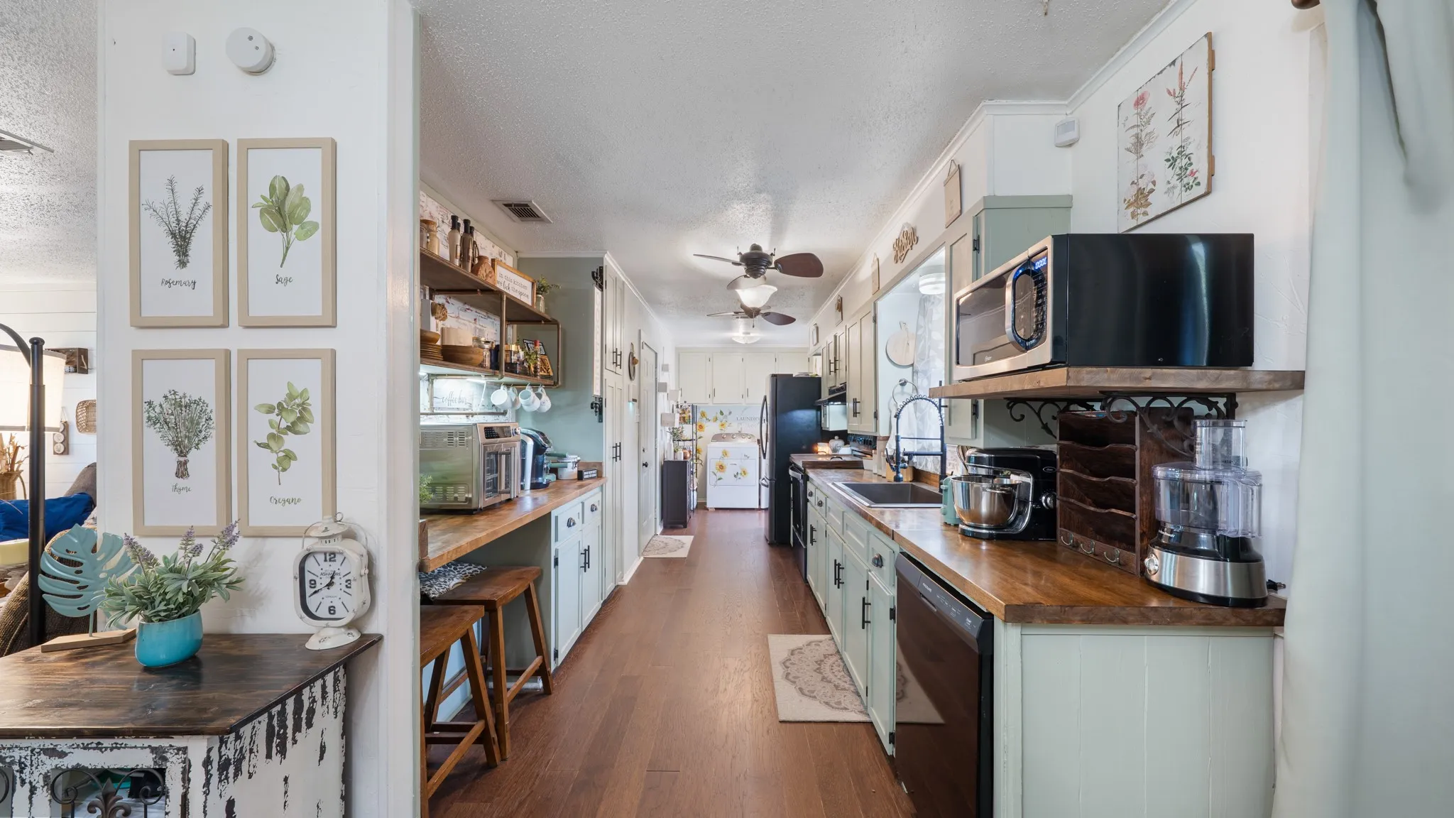 Galley kitchen featuring wood-finish flooring, light green cabinetry, and wood countertops