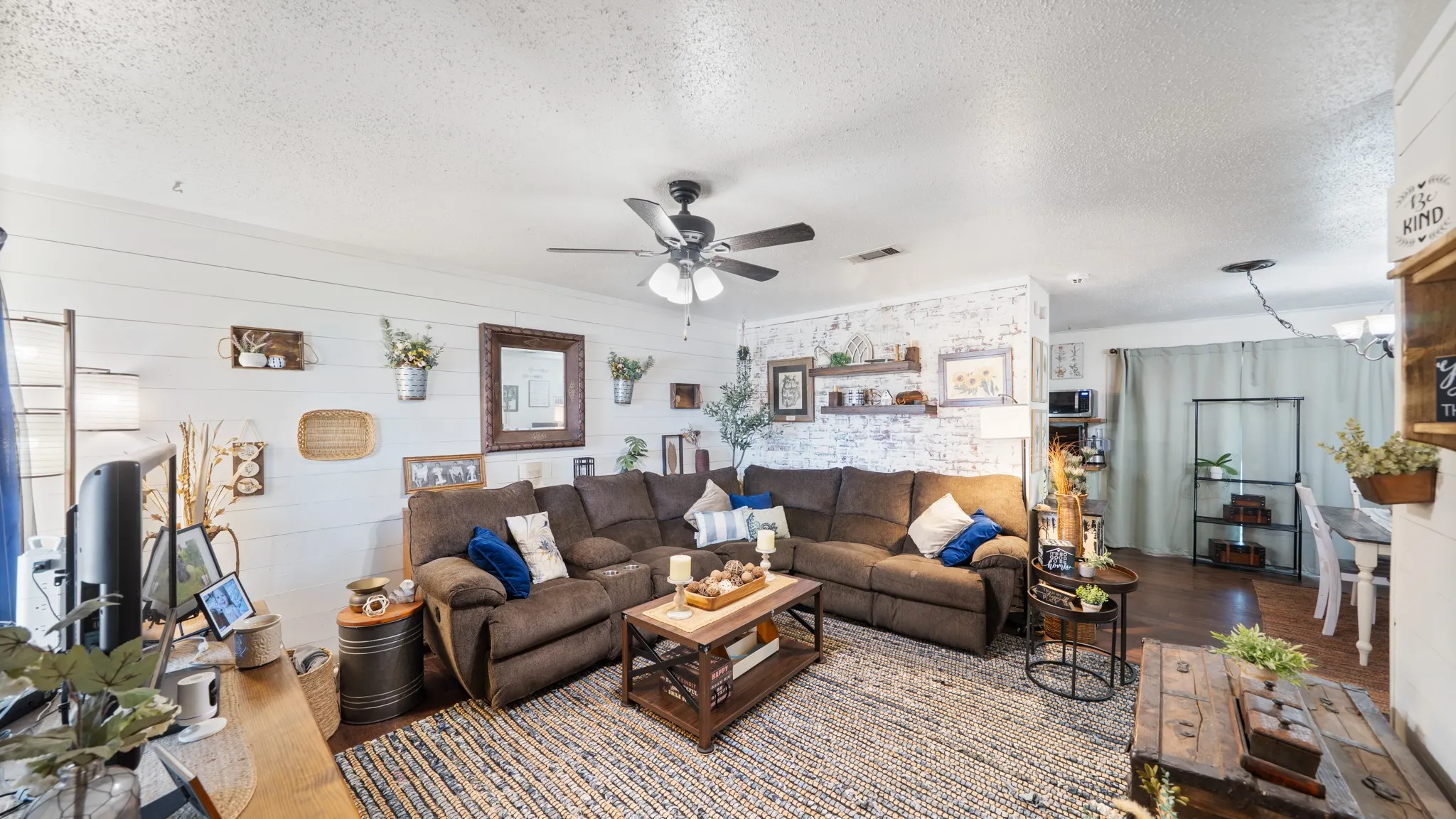 Shiplap accent walls, wood-finish flooring, ceiling fan, and built-in shelving