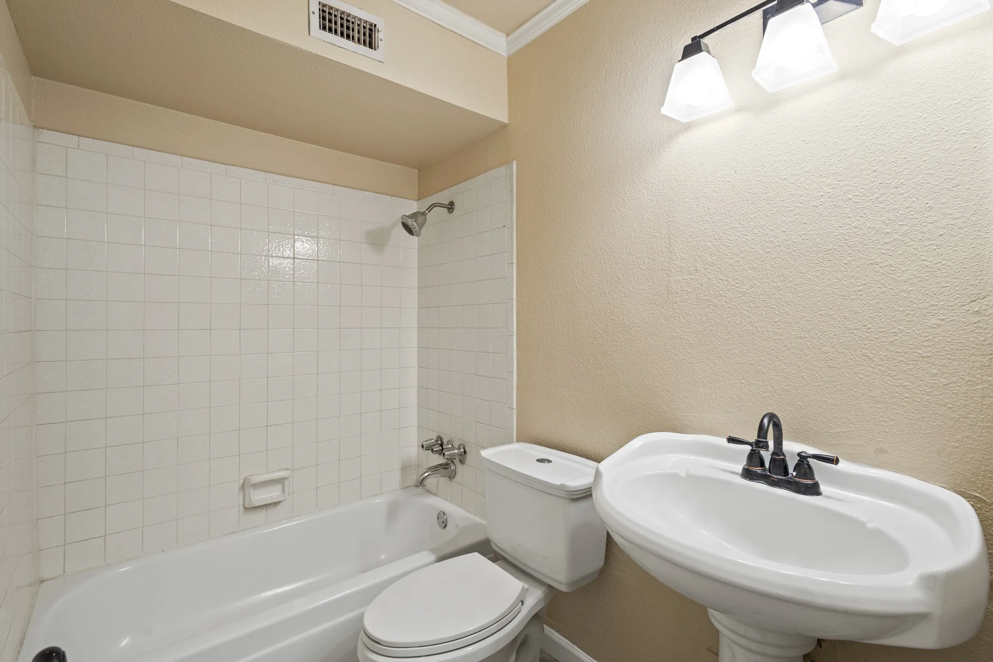 Full bath with a textured wall, bathing tub / shower combination, and crown molding