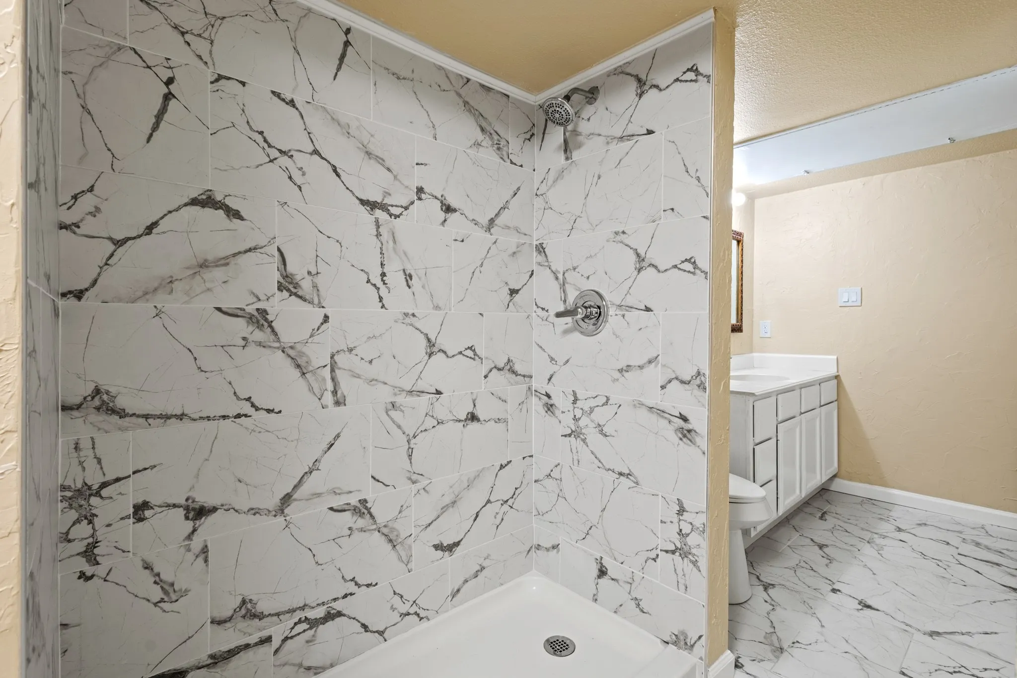 Full bath featuring marble finish floors, tiled shower, vanity, and crown molding