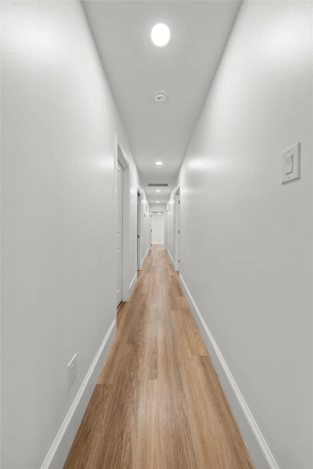Hall with light wood finished floors and recessed lighting