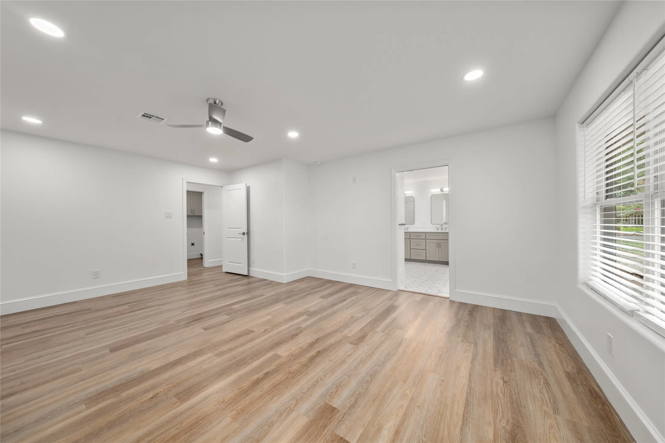 Unfurnished bedroom featuring light wood-type flooring, recessed lighting, ensuite bathroom, and a ceiling fan