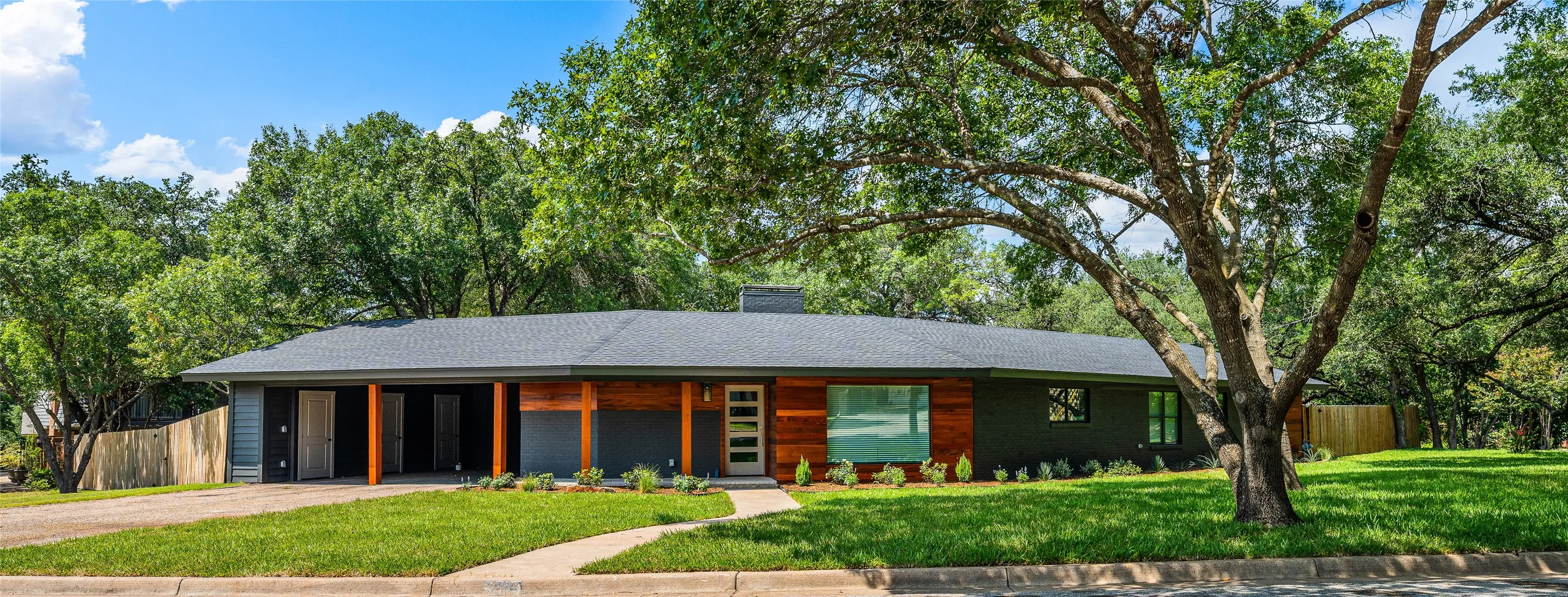 View of front of house featuring concrete driveway, a chimney, covered porch, and a carport