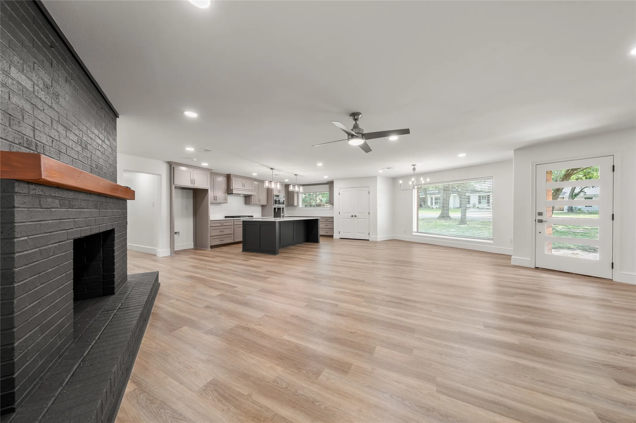 Unfurnished living room featuring recessed lighting, light wood finished floors, a fireplace, a ceiling fan, and a chandelier