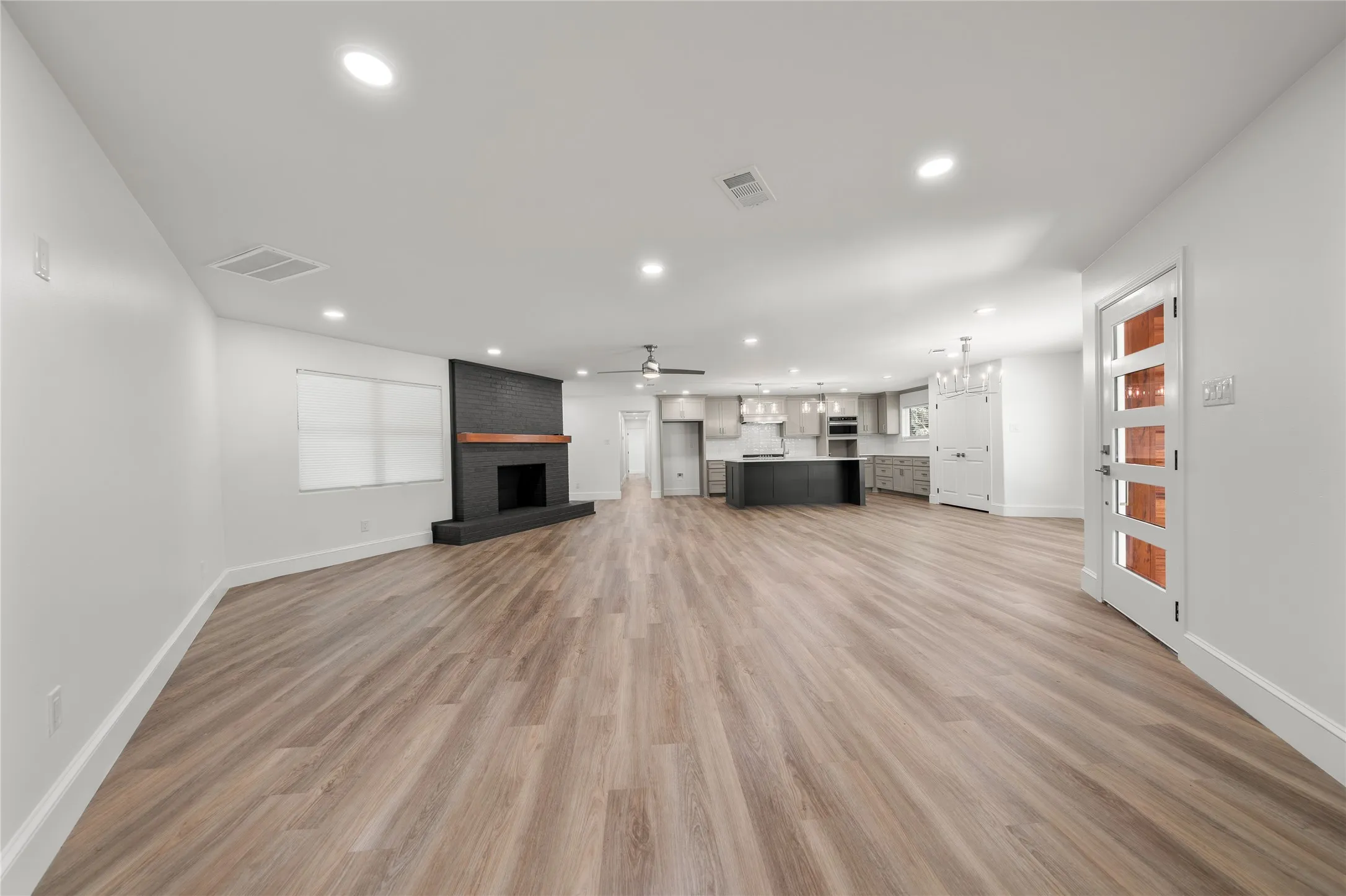 Unfurnished living room with a ceiling fan, recessed lighting, light wood-style floors, and a brick fireplace