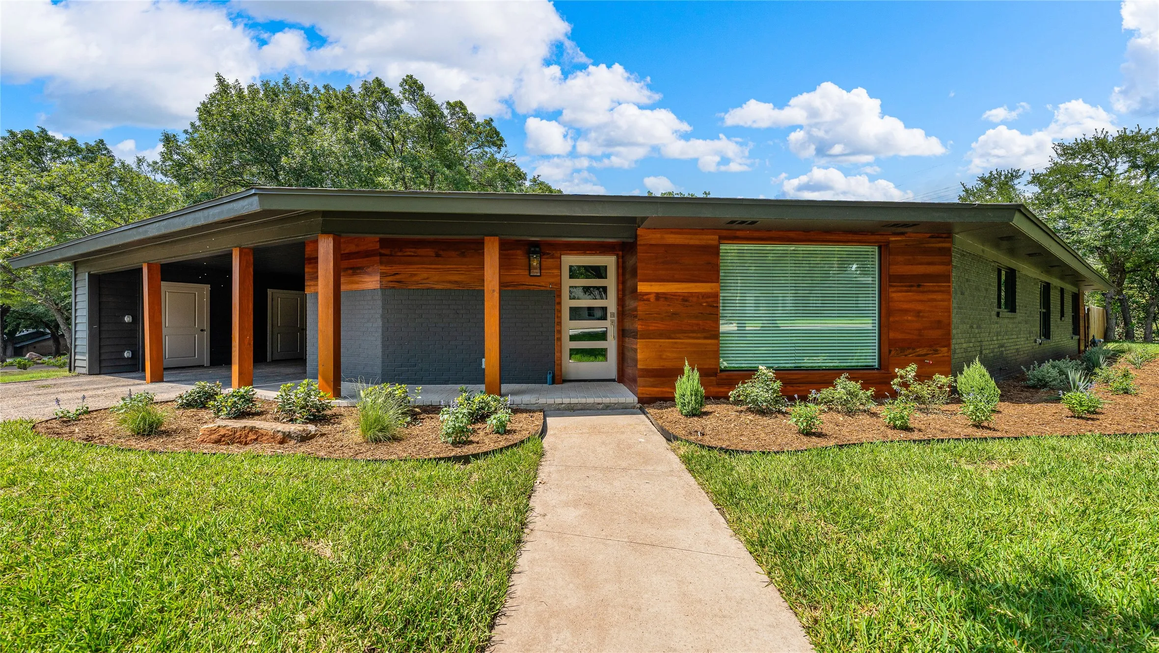 Modern home featuring a front lawn, a porch, and brick siding