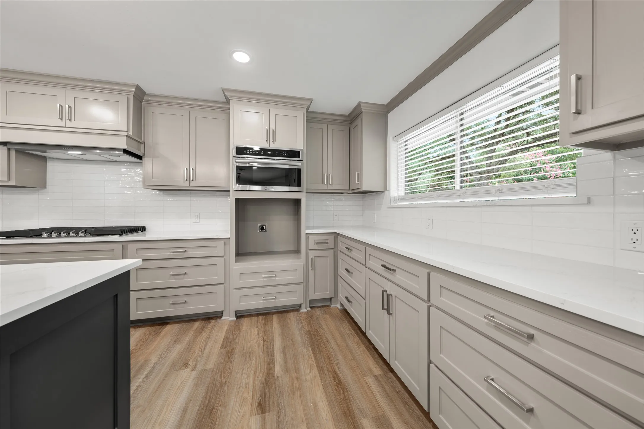 Kitchen with gray cabinetry, light wood-style floors, crown molding, decorative backsplash, and recessed lighting