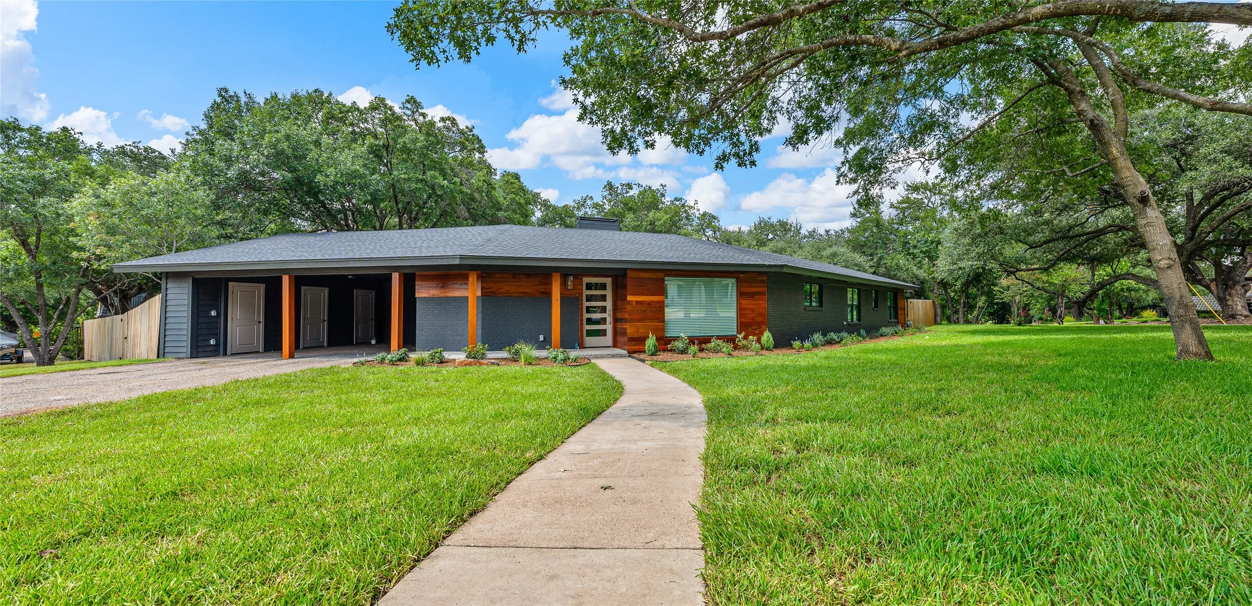 Contemporary house with driveway, a front lawn, a shingled roof, and an attached carport
