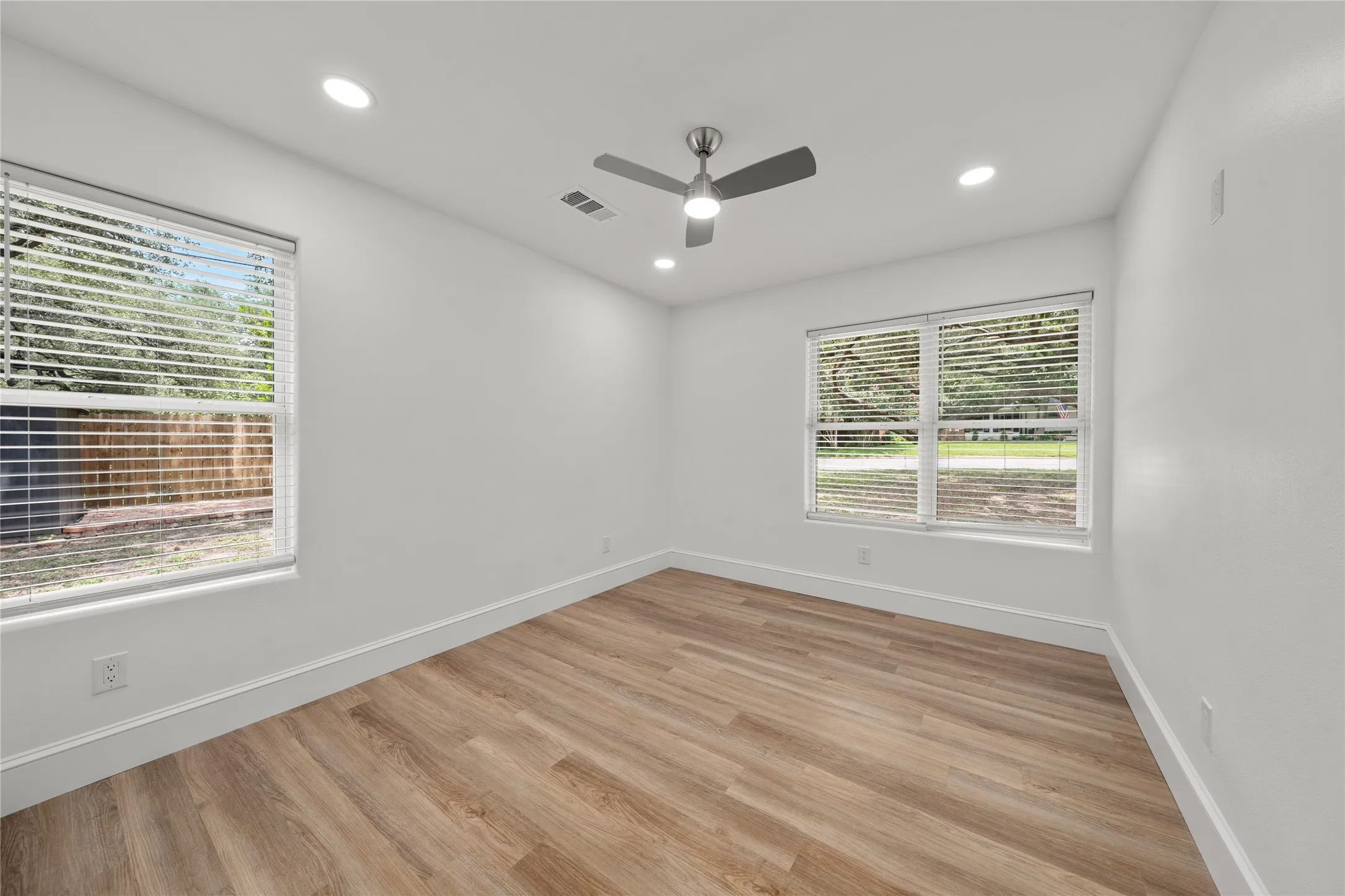 Empty room with healthy amount of natural light, light wood finished floors, recessed lighting, and a ceiling fan