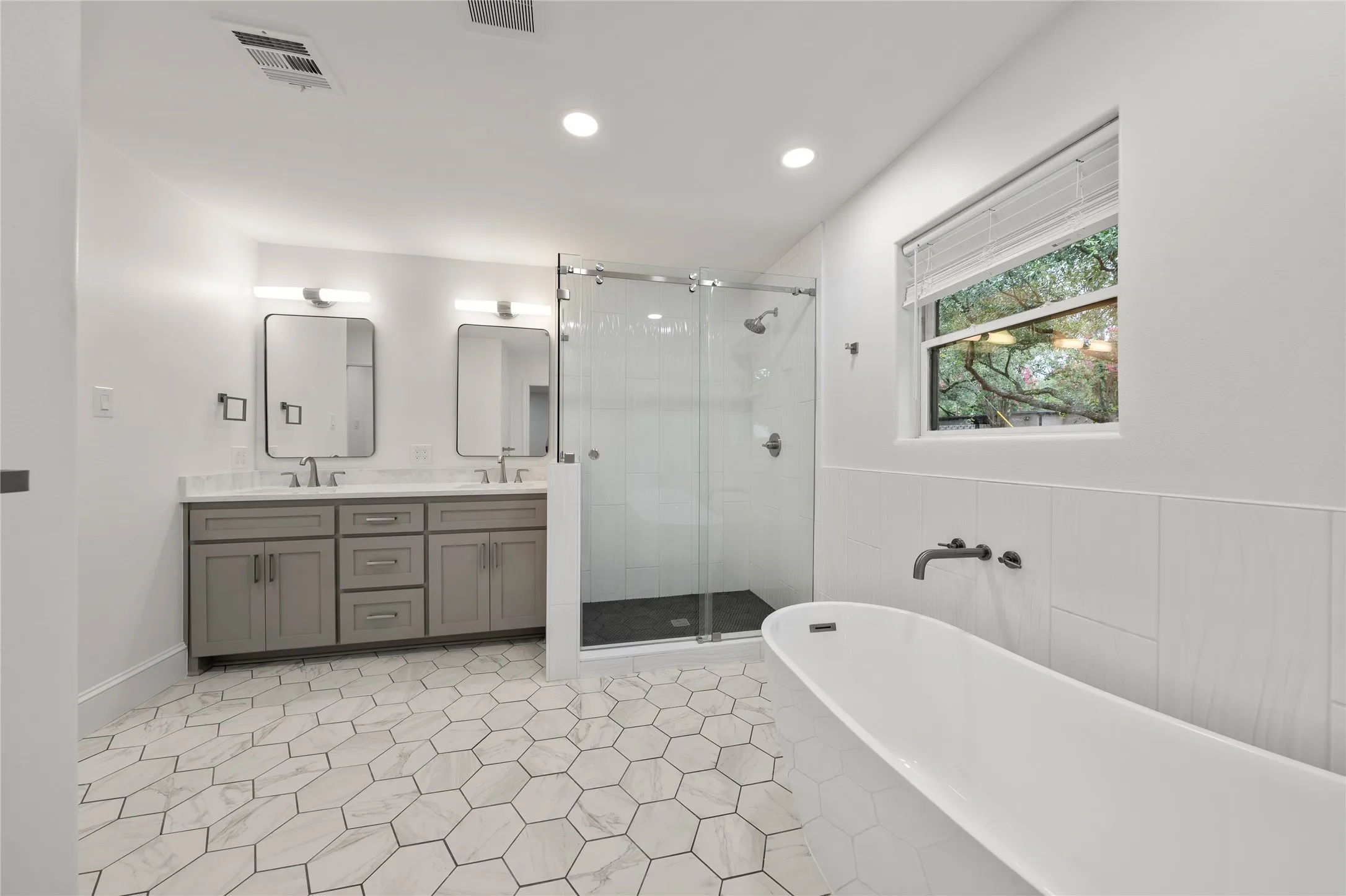 Full bath with a freestanding tub, double vanity, a shower stall, and recessed lighting