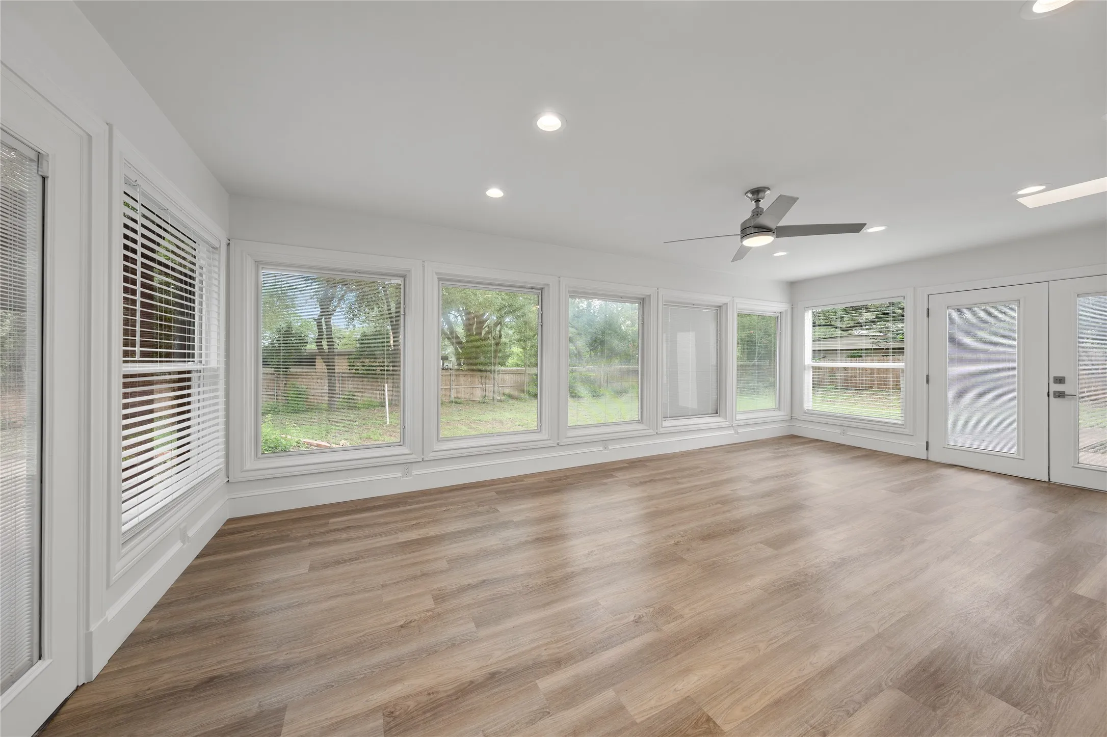 Unfurnished sunroom with wood finished floors, recessed lighting, and french doors