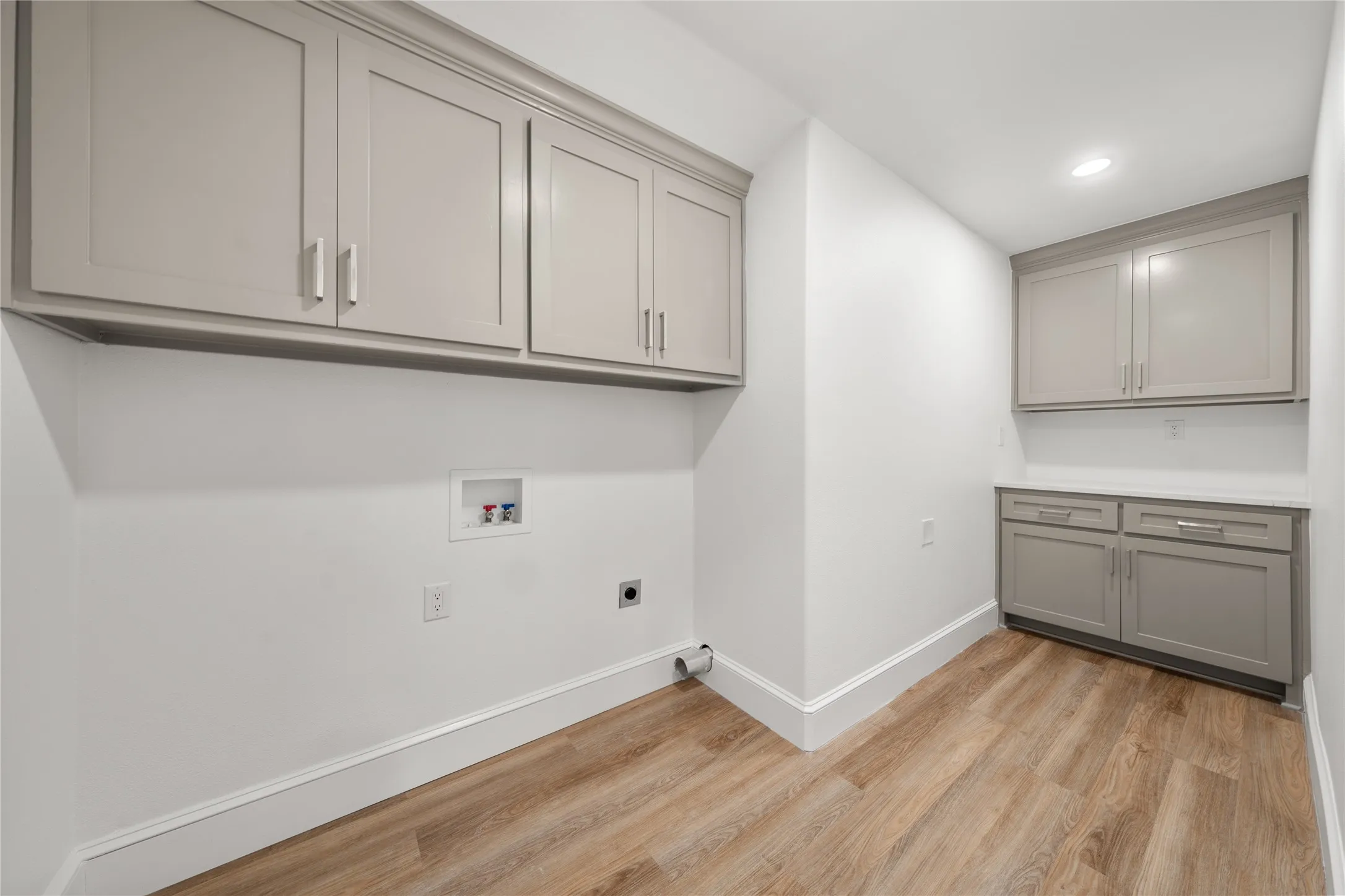 Washroom featuring hookup for an electric dryer, hookup for a washing machine, cabinet space, light wood finished floors, and recessed lighting