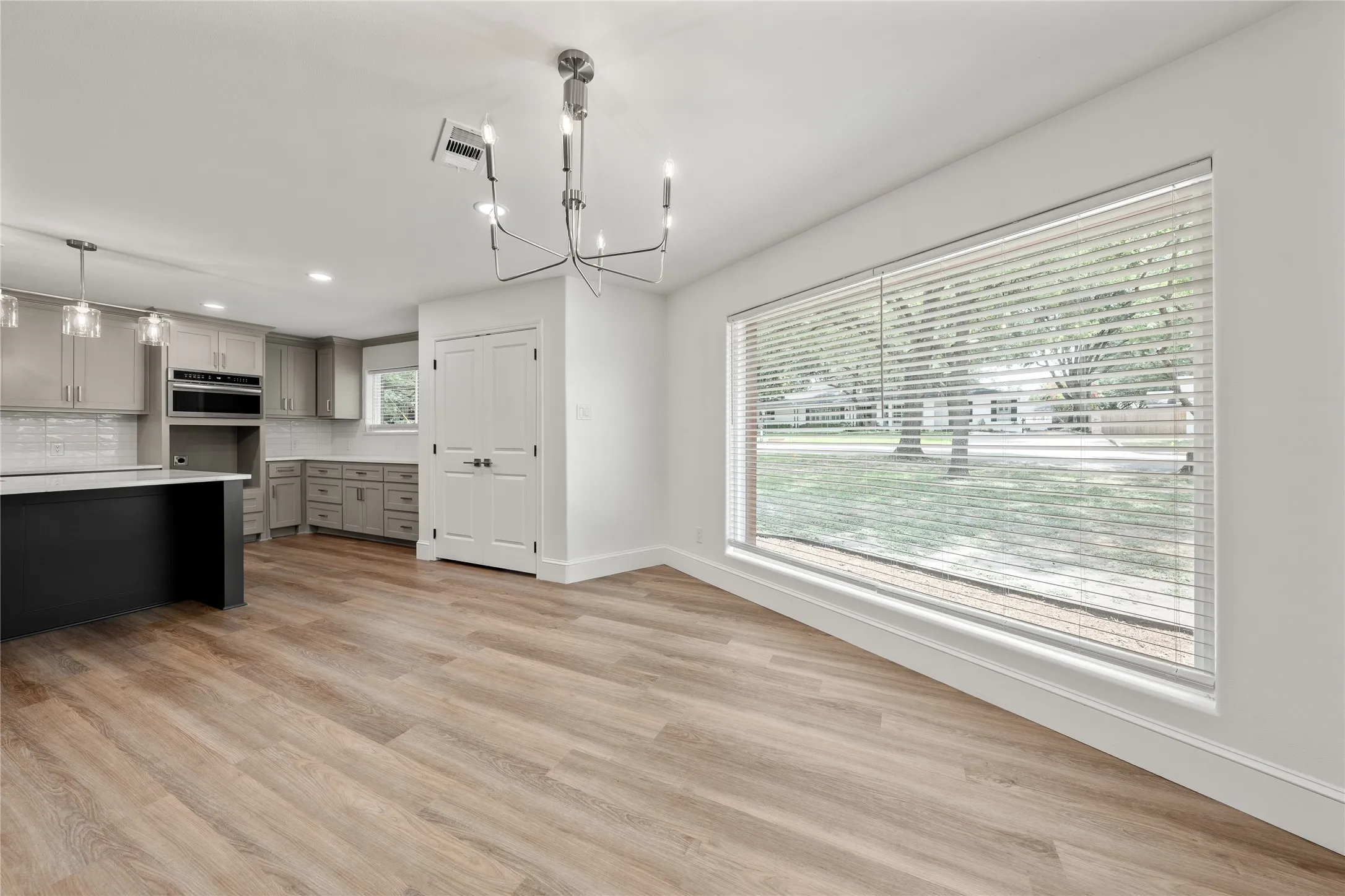 Kitchen featuring gray cabinets, a chandelier, hanging light fixtures, light countertops, and recessed lighting