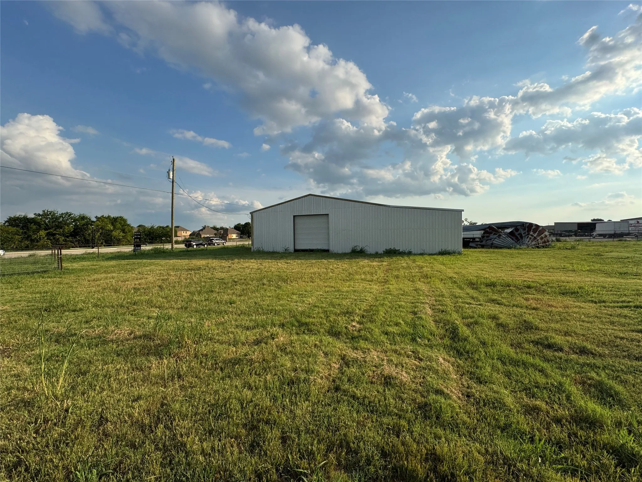 View of green lawn with a pole building, a detached garage, and an outbuilding