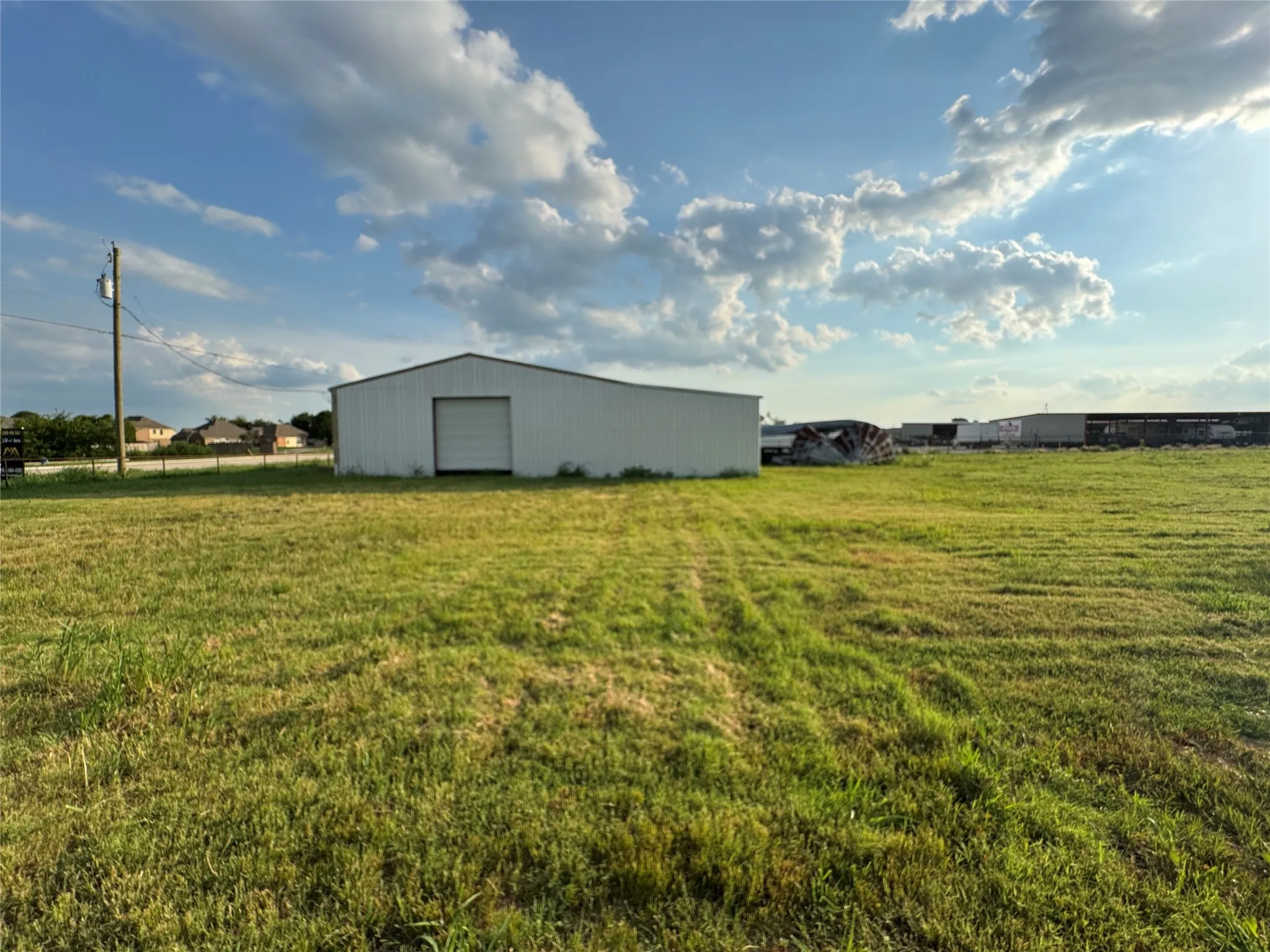 View of green lawn featuring an outbuilding and a garage