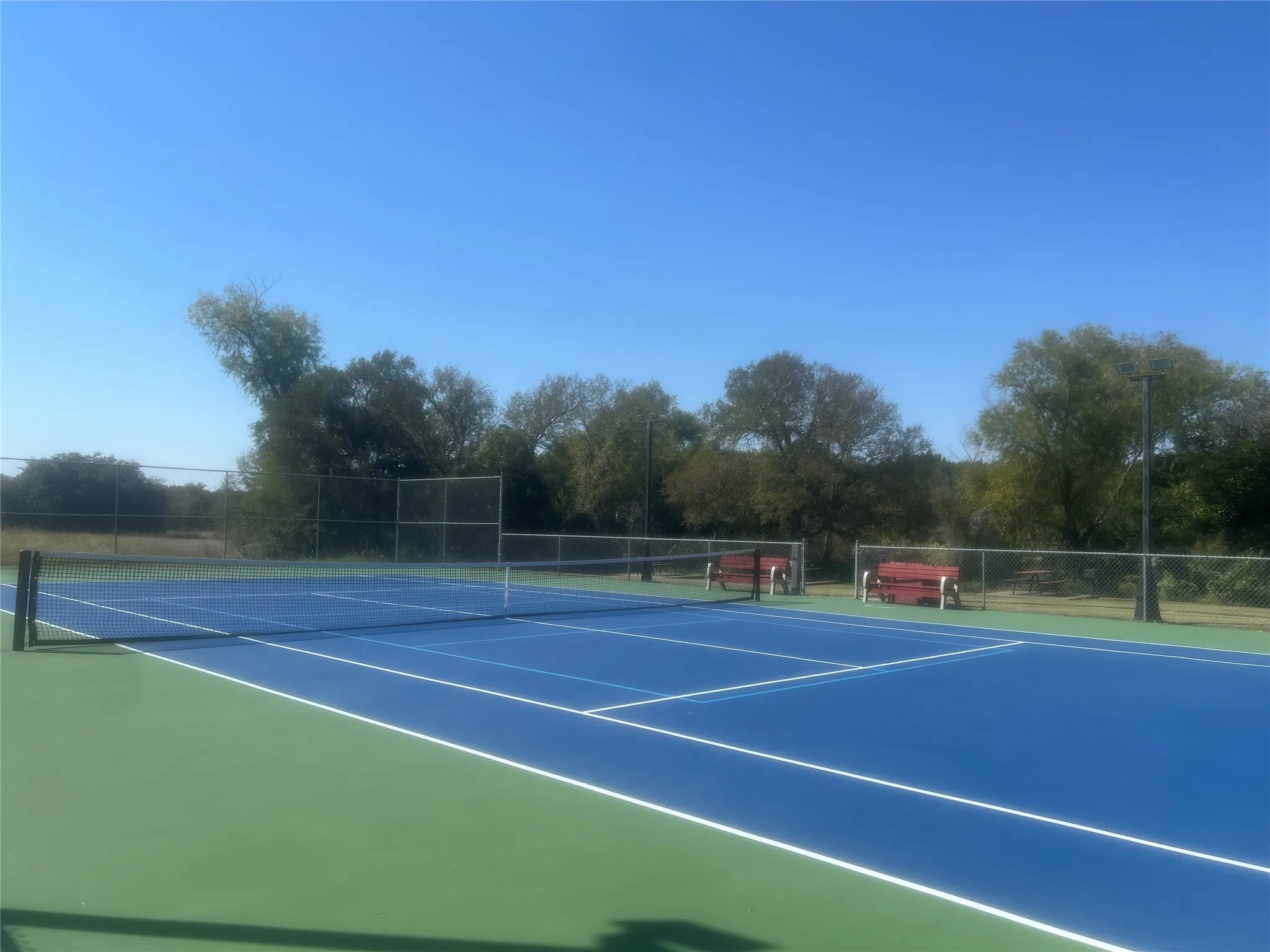 View of tennis court with community basketball court