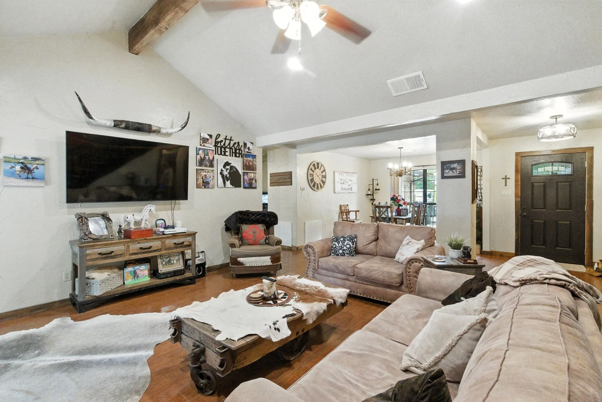 Living room with wood finished floors, ceiling fan, and a chandelier