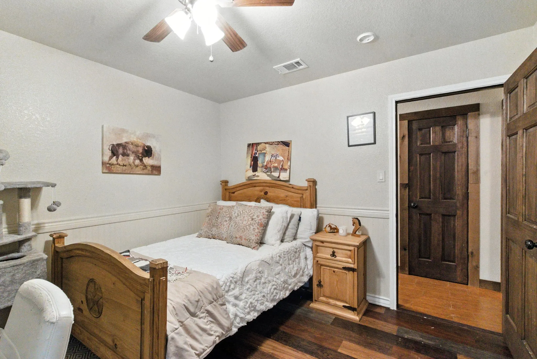 Bedroom with wainscoting, dark wood finished floors, ceiling fan, and a textured ceiling