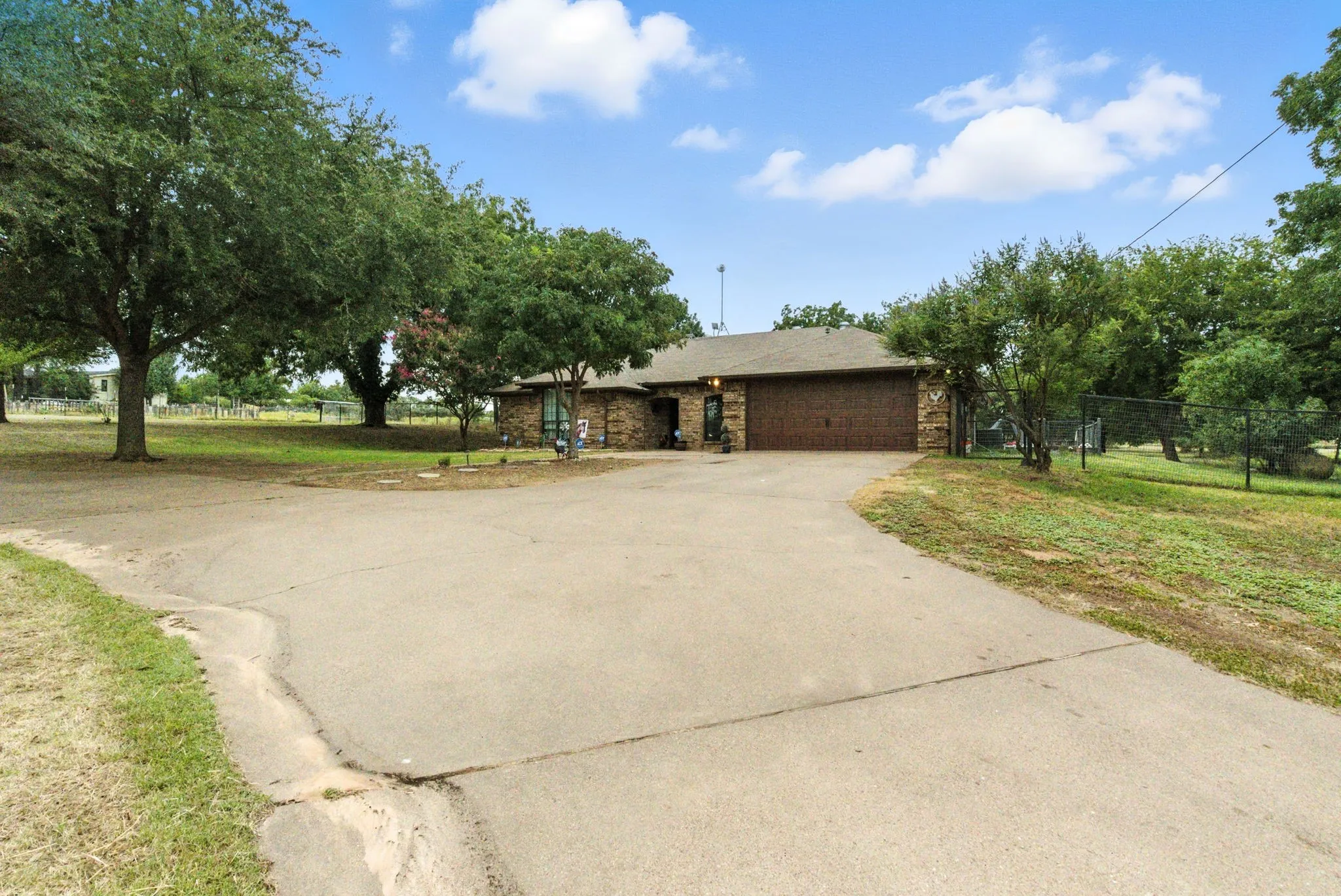 Ranch-style house featuring an attached garage, concrete driveway, and stone siding