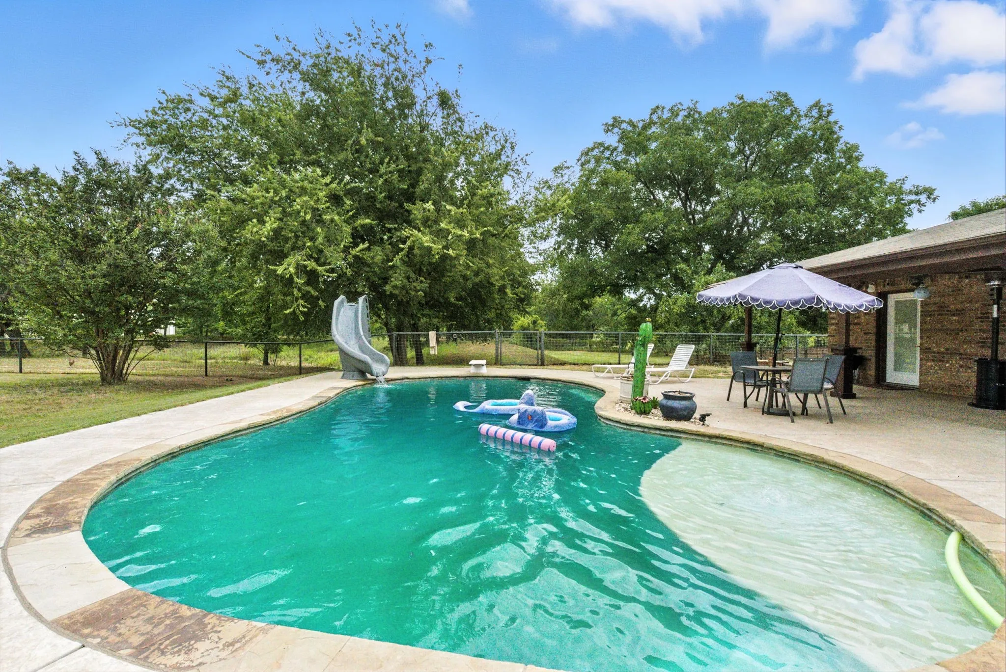 View of pool with a water slide and a patio area