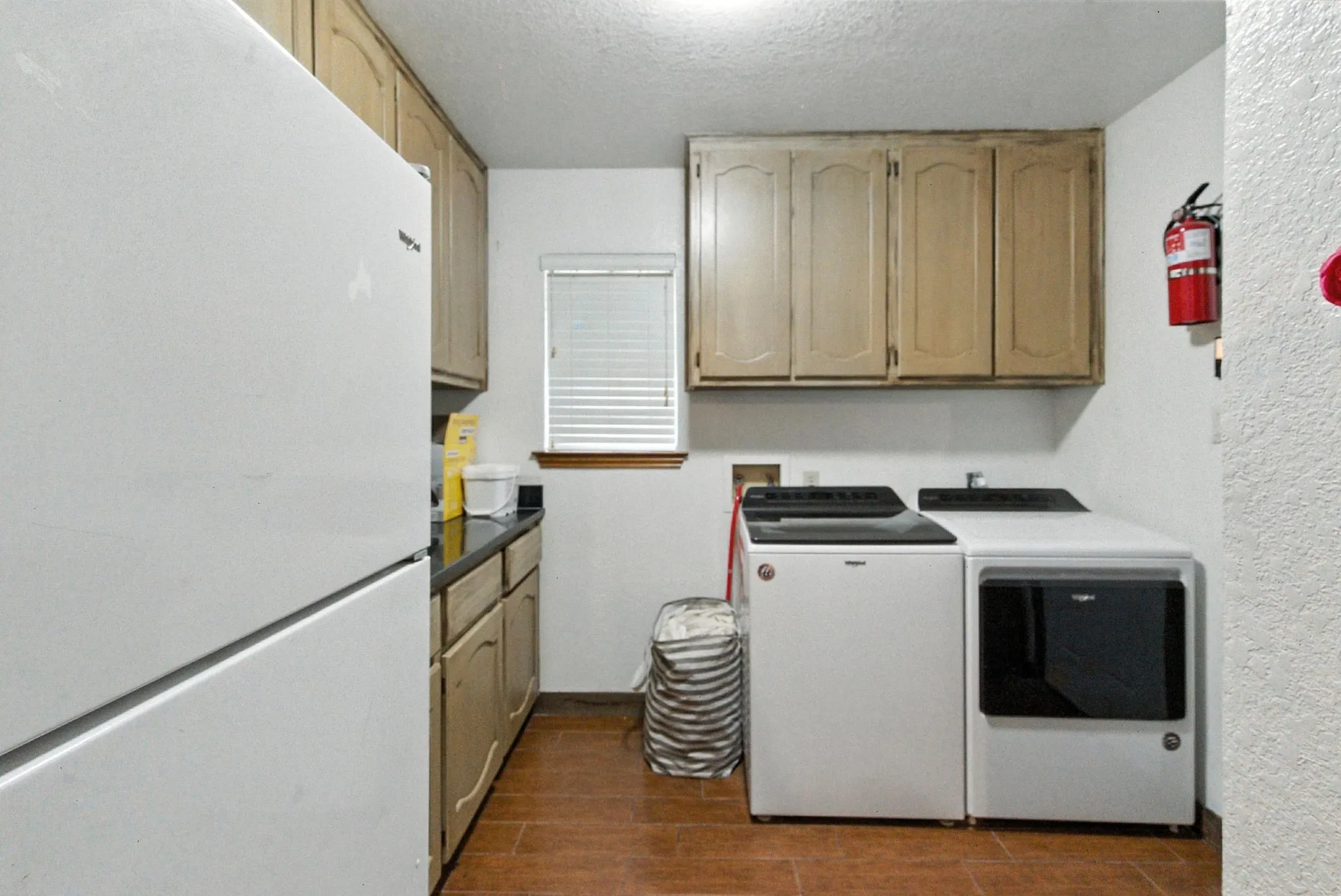 Laundry area with cabinet space, independent washer and dryer, dark wood-type flooring, a textured ceiling, and a textured wall