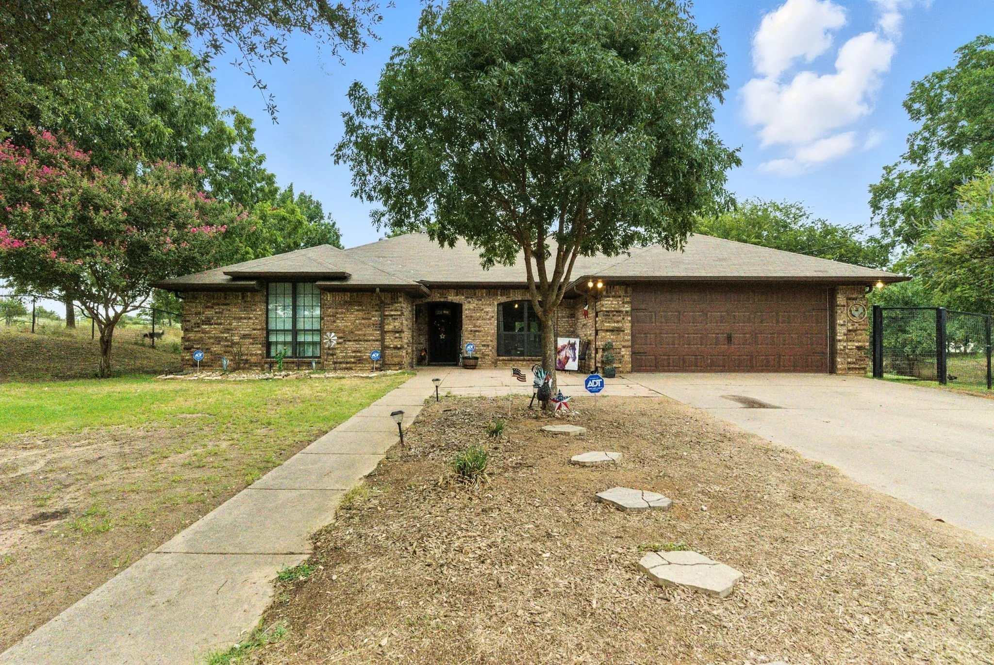 Ranch-style home featuring an attached garage, concrete driveway, brick siding, and roof with shingles