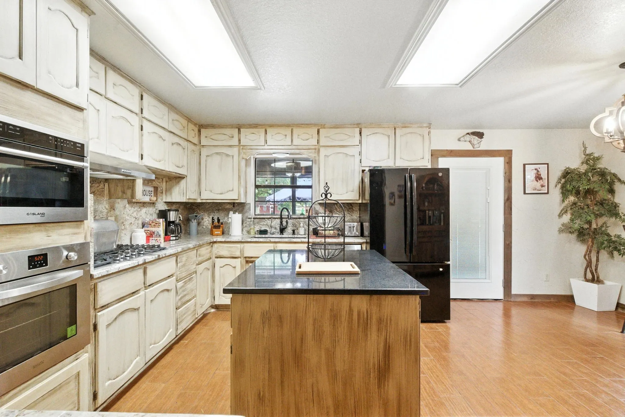 Kitchen featuring appliances with stainless steel finishes, a kitchen island, light wood-type flooring, tasteful backsplash, and a textured ceiling