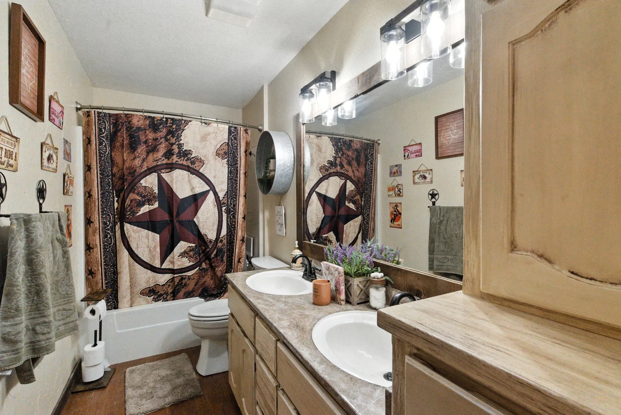 Bathroom with double vanity, shower / bath combo with shower curtain, and wood finished floors