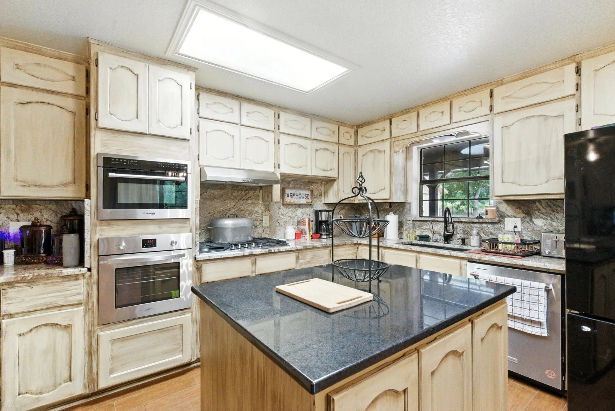 Kitchen with appliances with stainless steel finishes, light wood-style floors, a kitchen island, and tasteful backsplash
